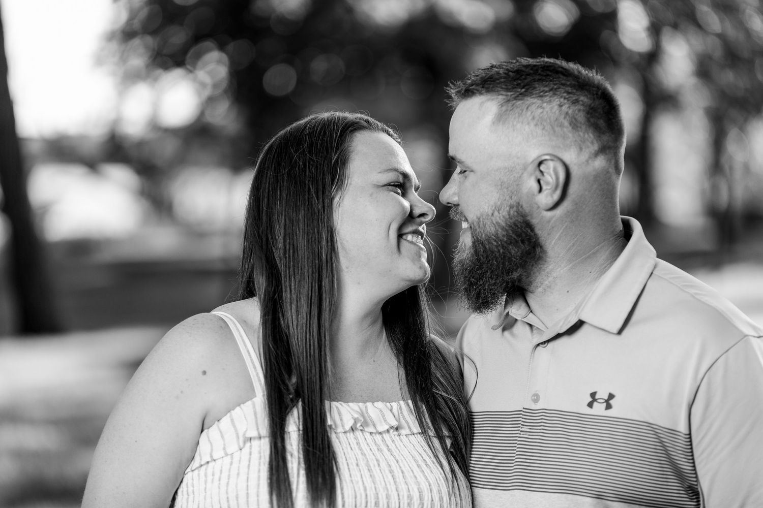 Black and white romantic portrait of a couple sharing a tender moment outdoors at golden hour.