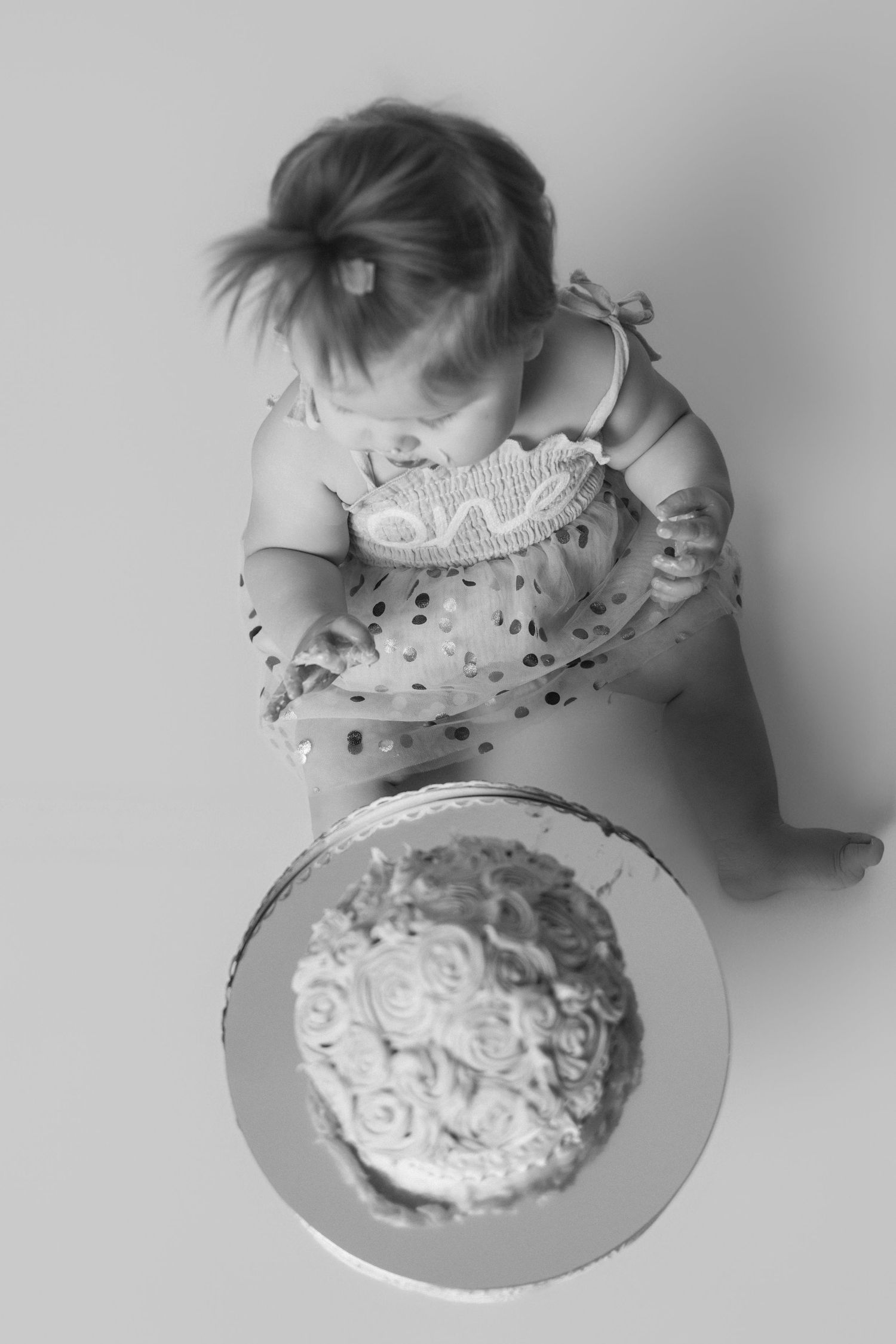 A sequence of black and white photos showing someone eating a frosted cake from above.