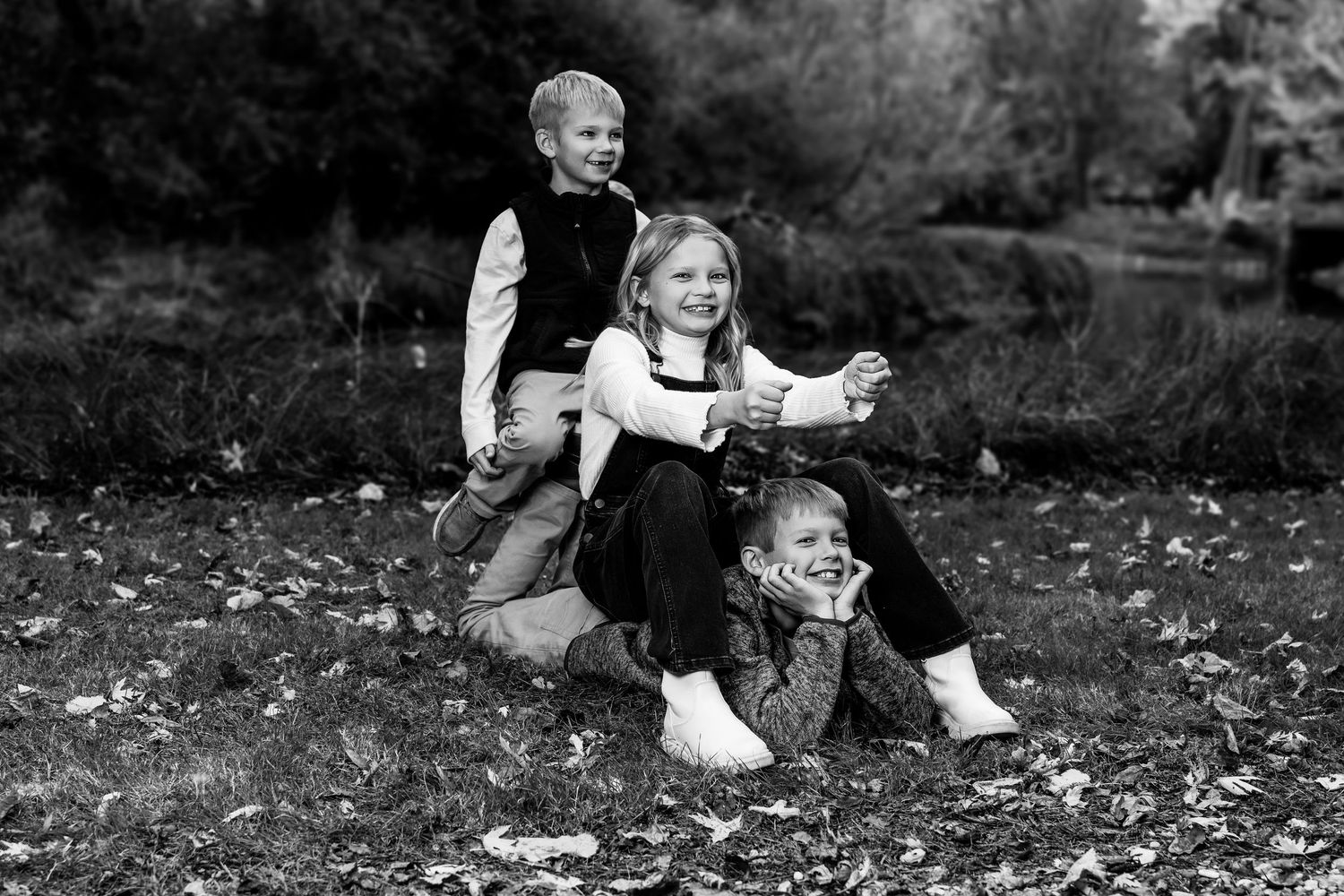 Family sitting together on fallen leaves during an autumn outdoor photo session.