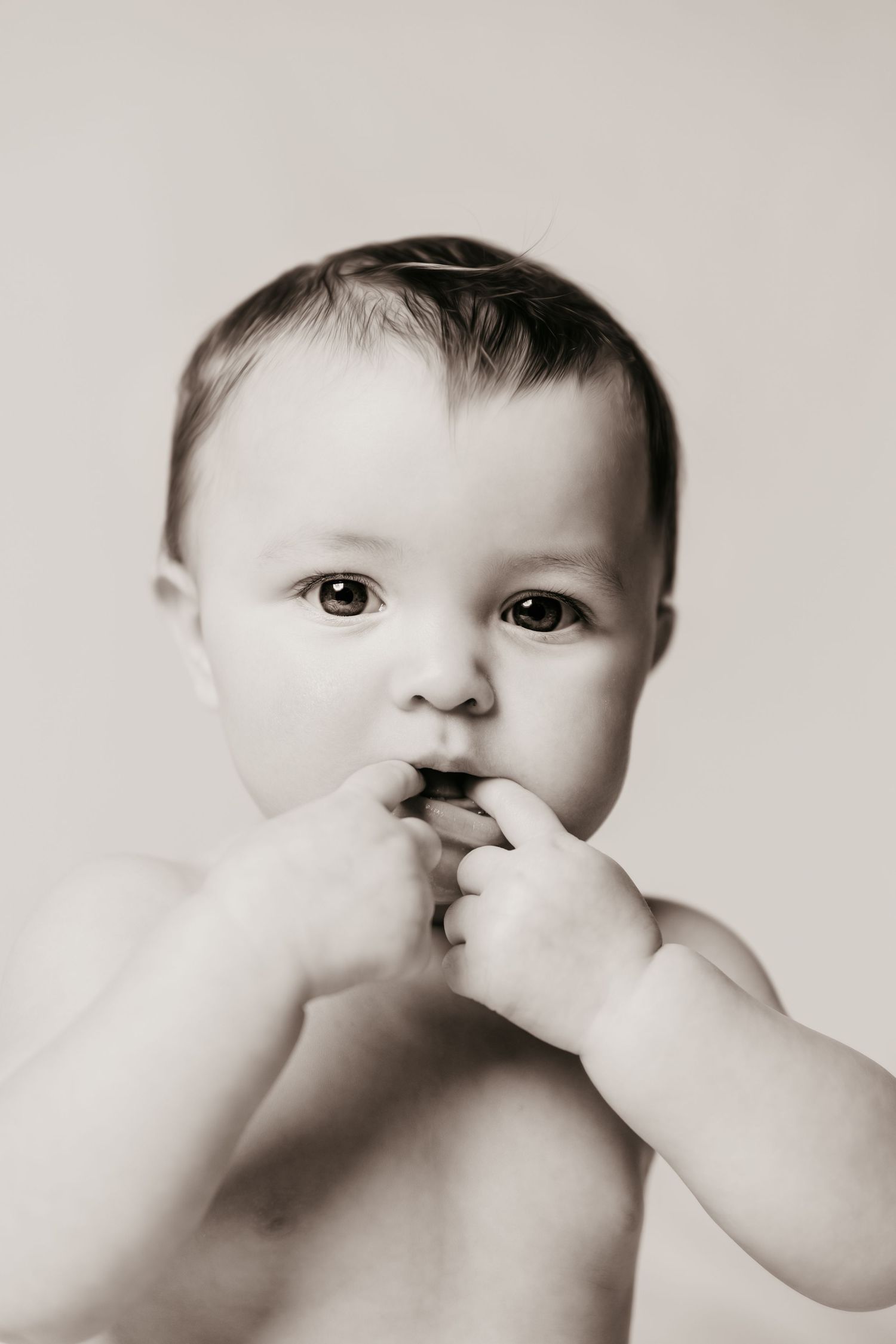Black and white artistic sequence showing a baby's face with hands covering their mouth in different poses.