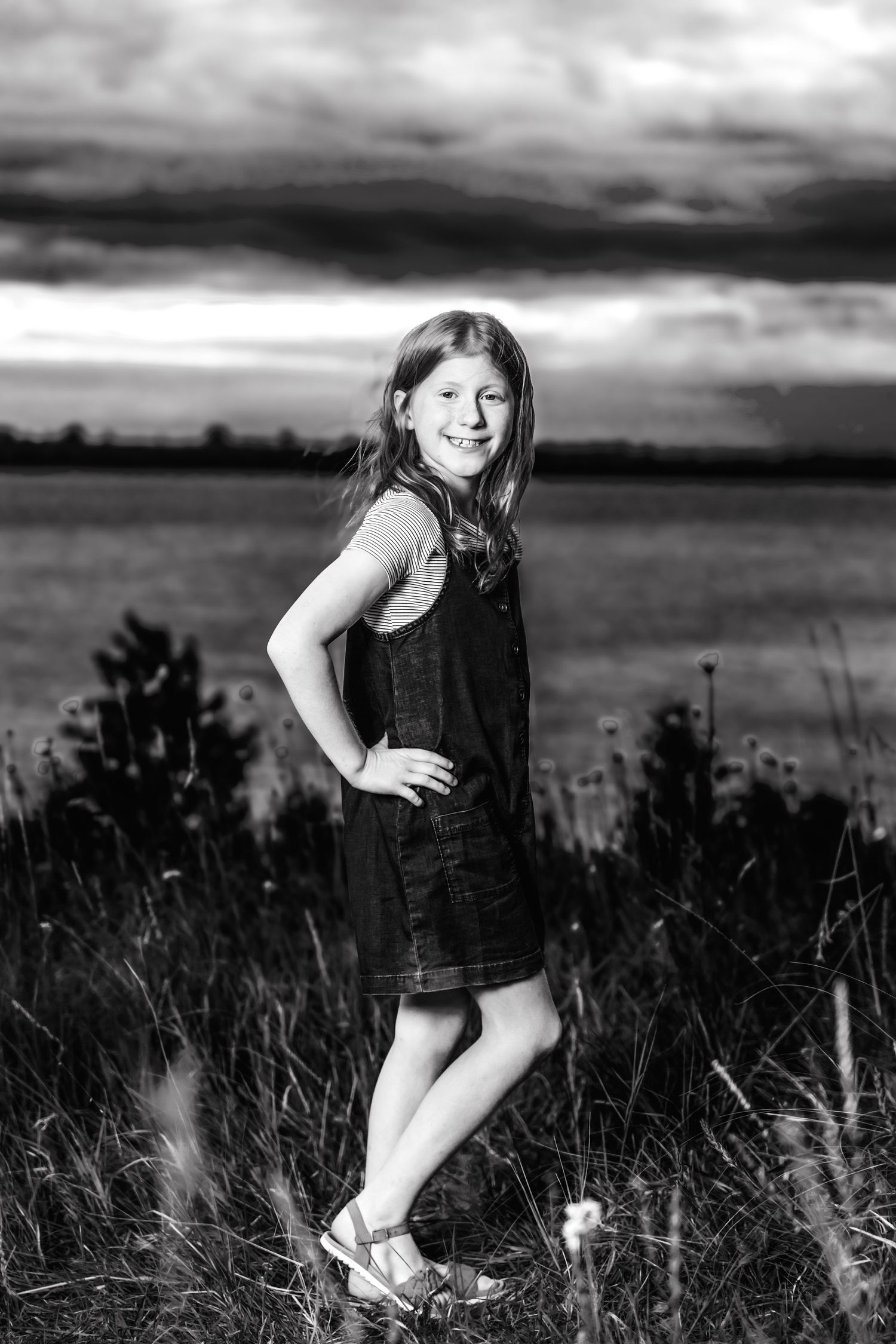 A series of seven black and white images showing someone posing playfully in tall grass.