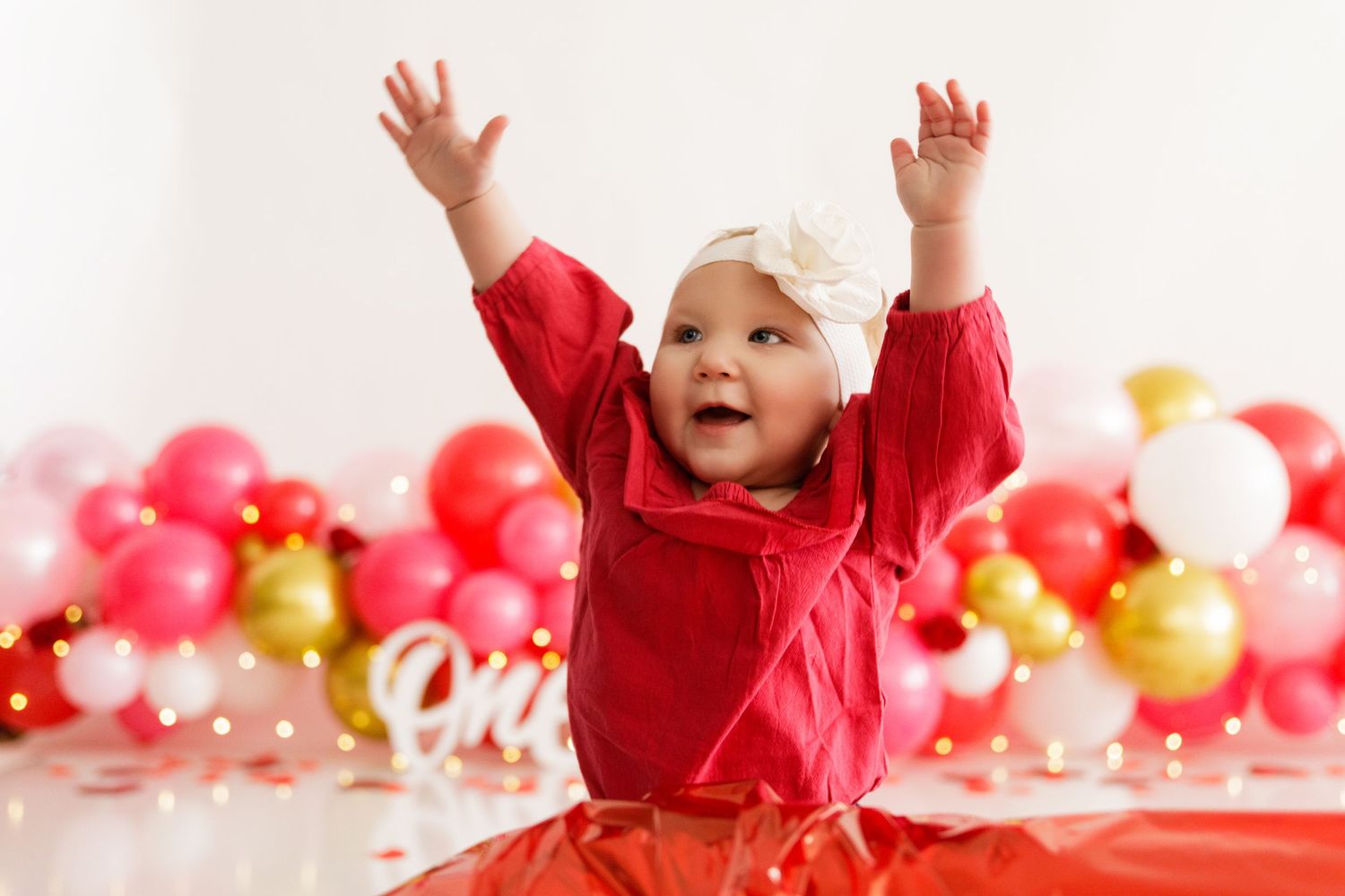 Celebratory scene with raised hands and red and gold balloon decorations.