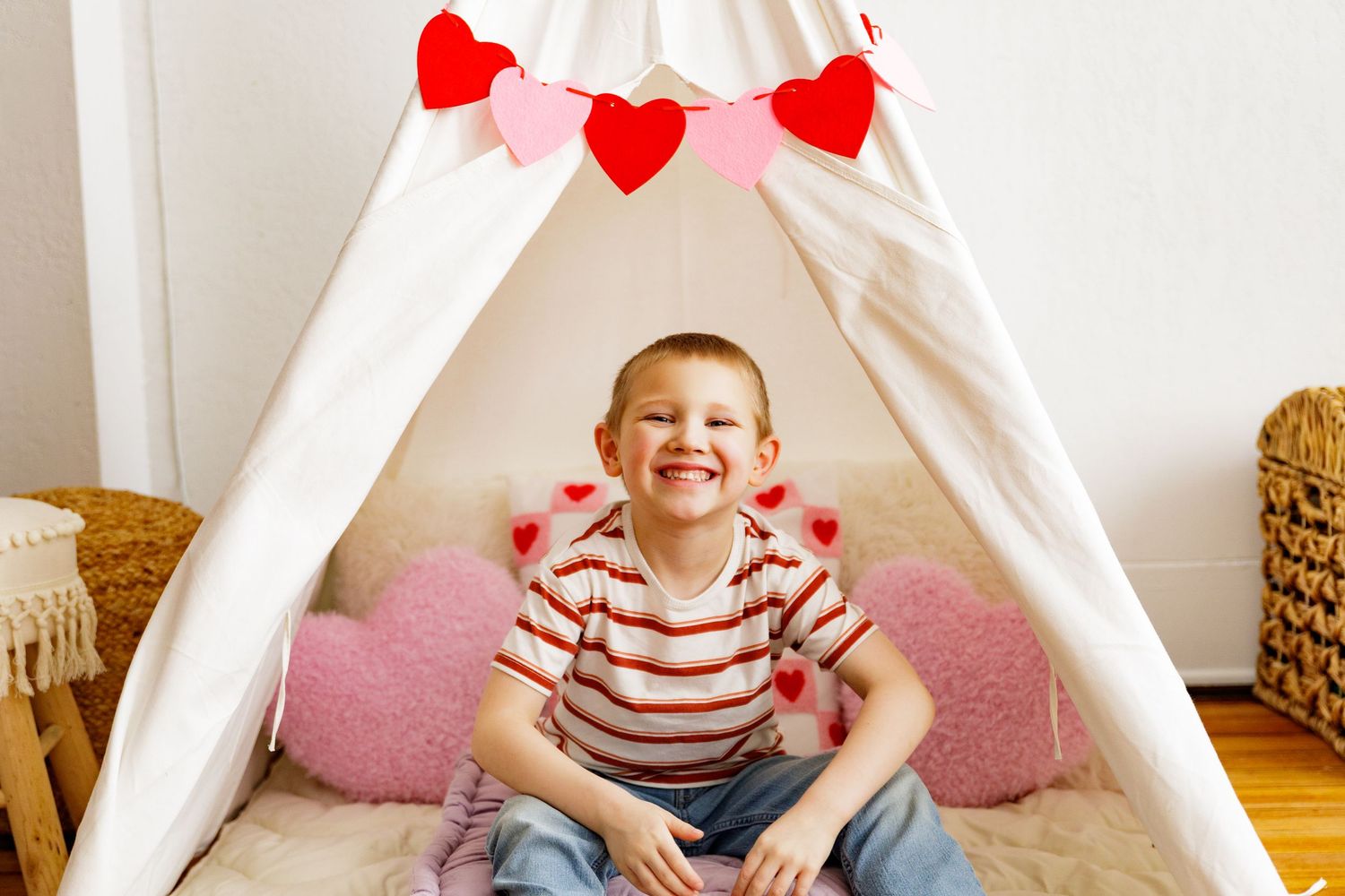 White teepee tent decorated with red hearts and pink cushions for a Valentine's day photoshoot.