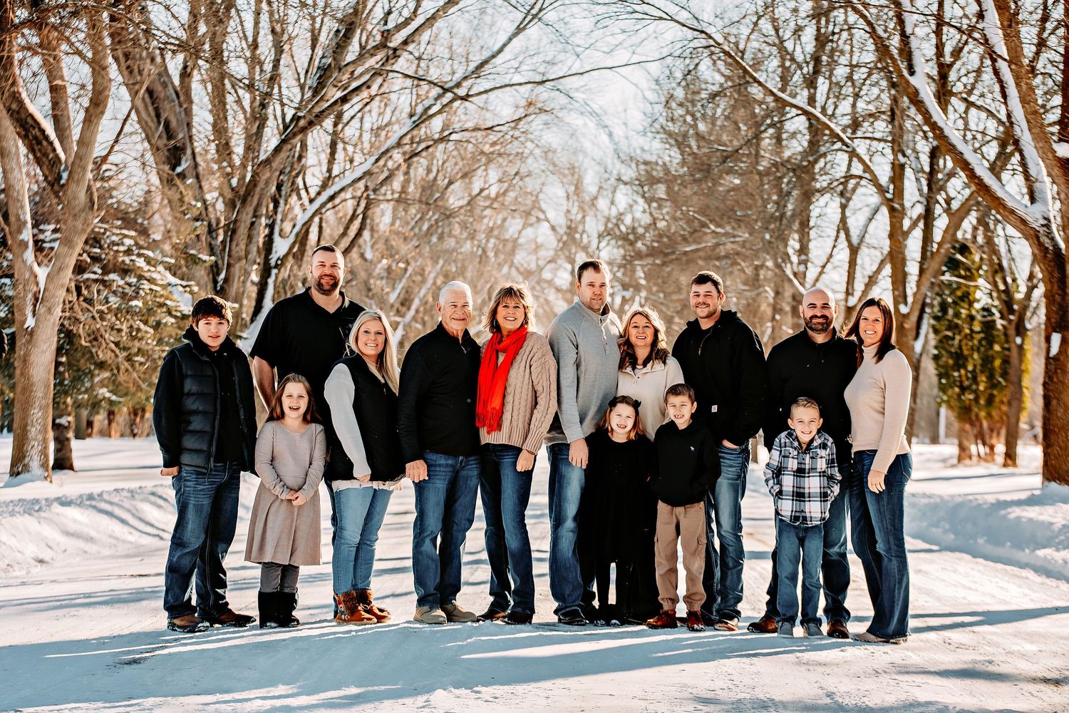 Group of people standing together in a snowy winter landscape with bare trees in the background.