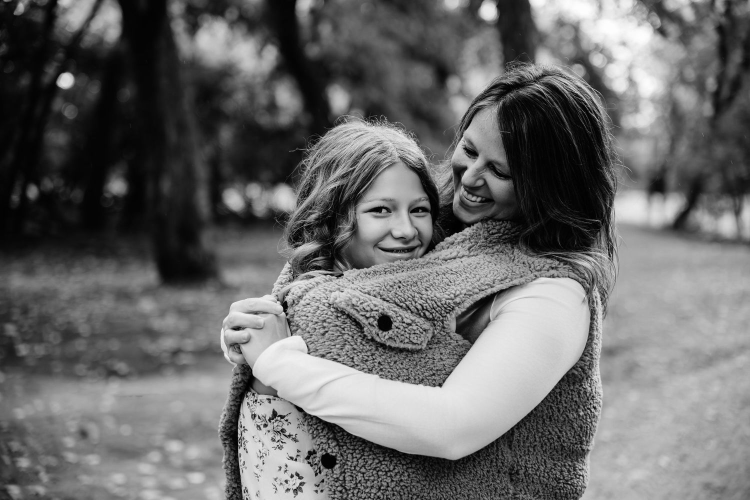 Family members share warm embraces and tender moments in a series of black and white outdoor portraits.