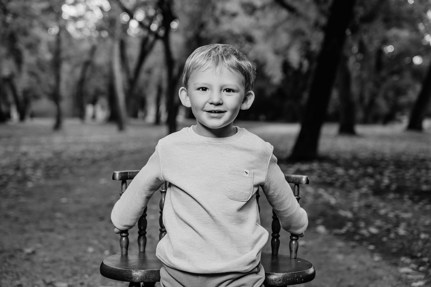 Black and white portrait of young child sitting outdoors.