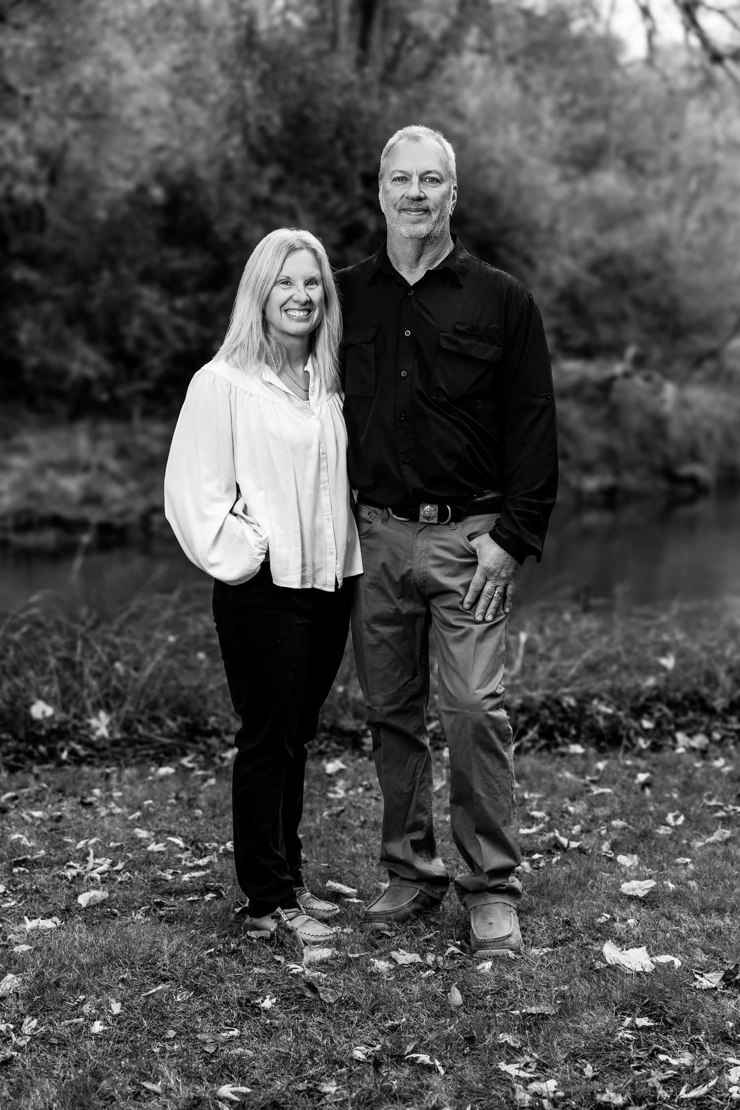 Black and white portraits in a natural outdoor setting with fallen leaves.