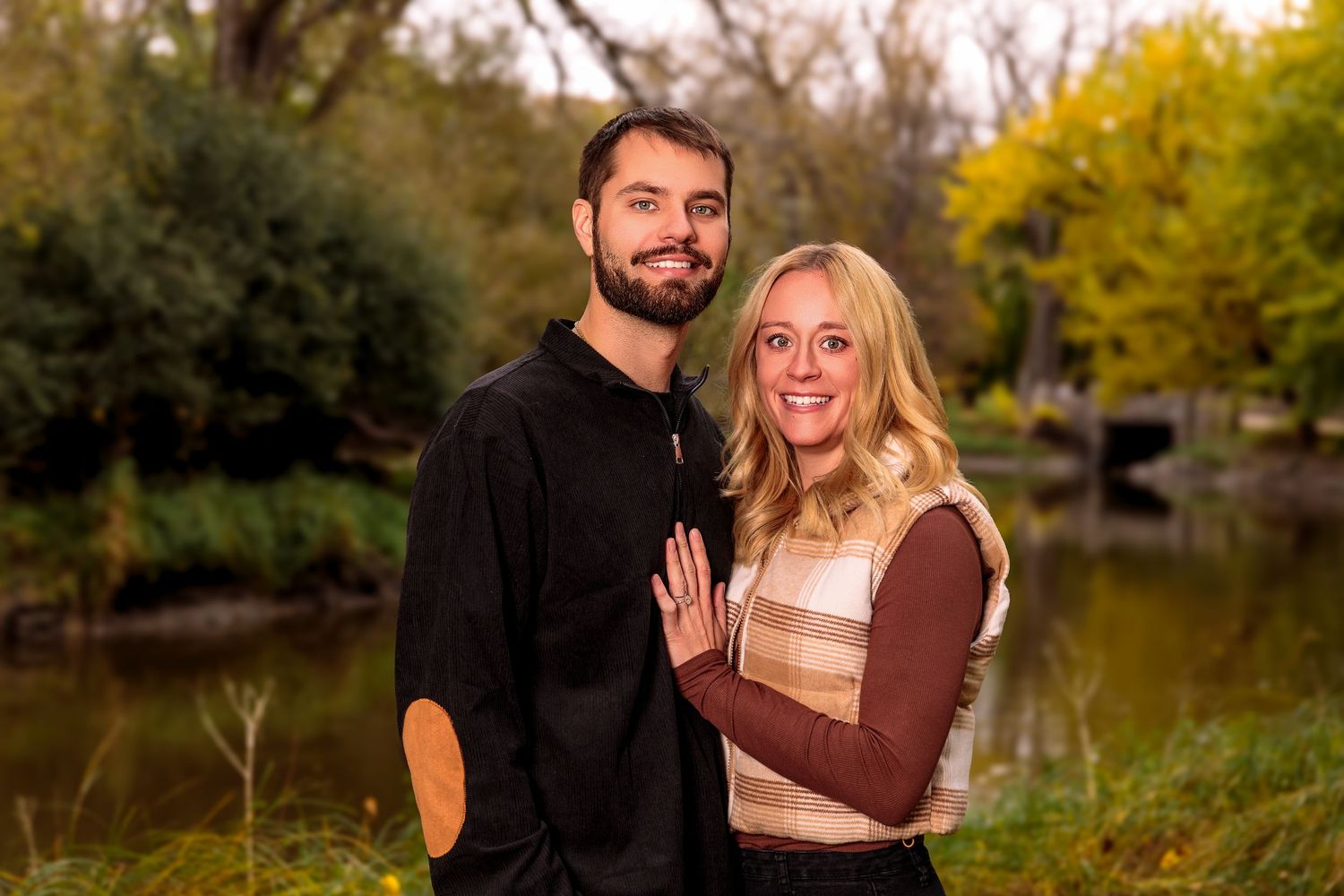Romantic autumn engagement photos by a lake with warm golden lighting.