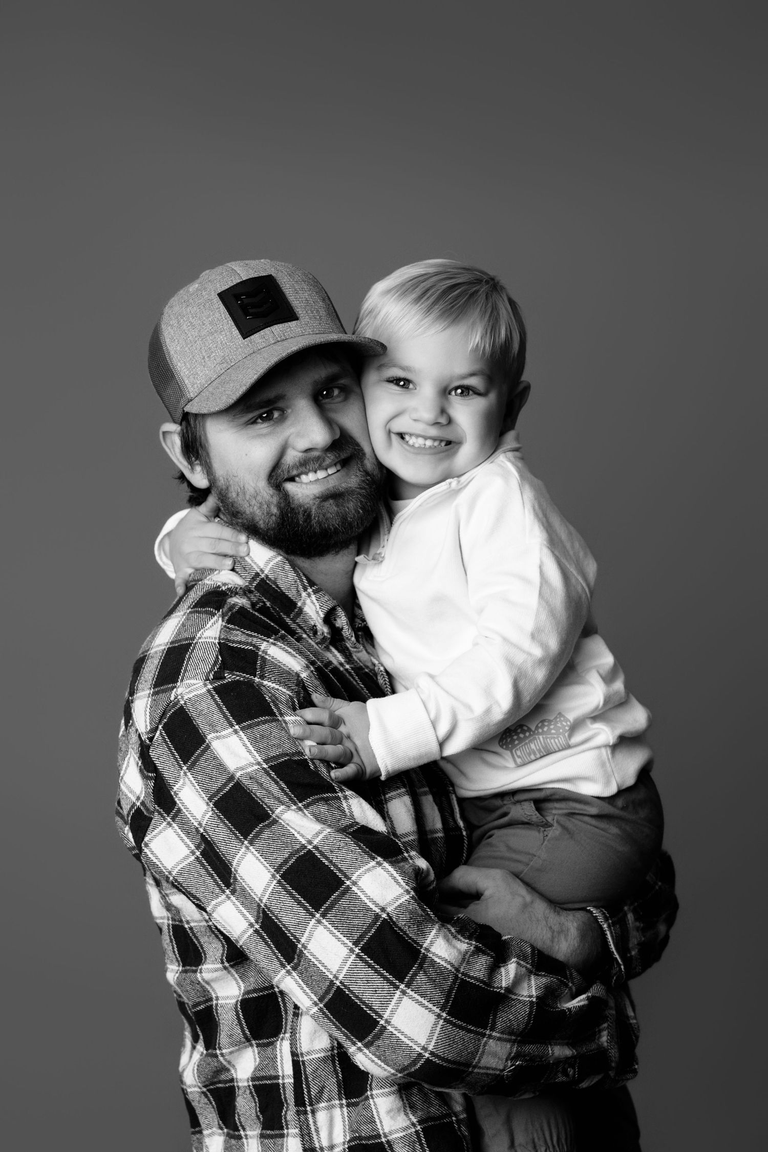 Series of black and white photos showing tender moments with plaid shirt against gray backdrop.