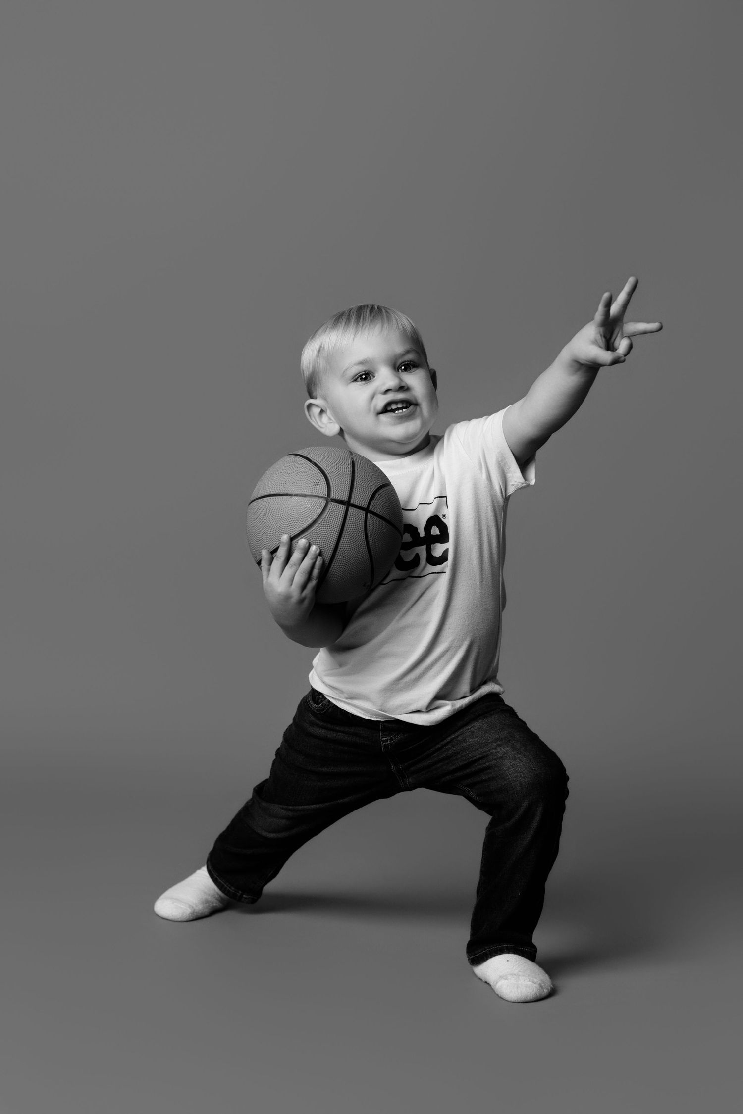 Dynamic black and white photos of young child striking playful poses with basketball.