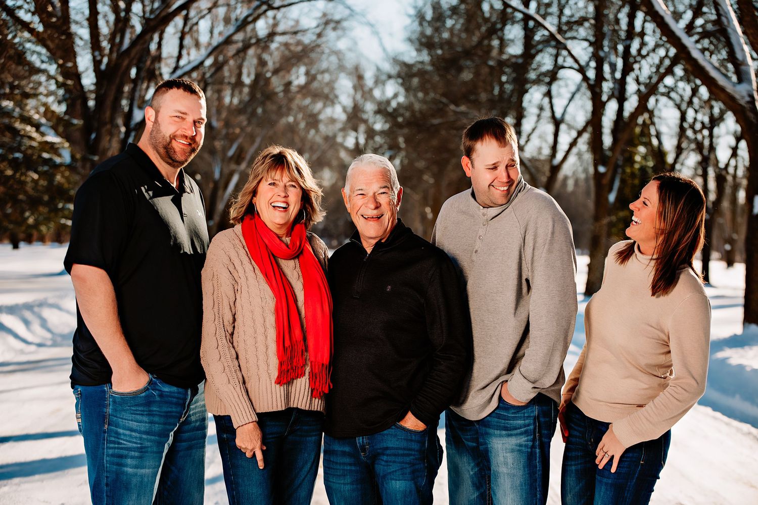 Extended family posing together on a snowy winter day with leafless trees in the background.