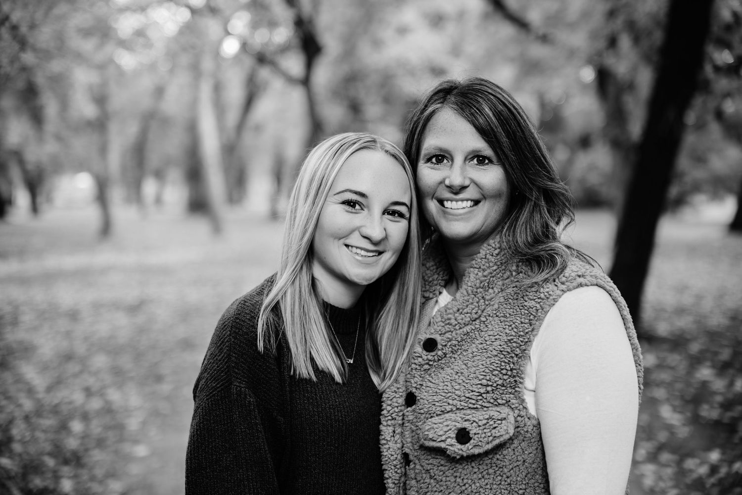 Casual outdoor family photoshoot with warm embraces among autumn trees.