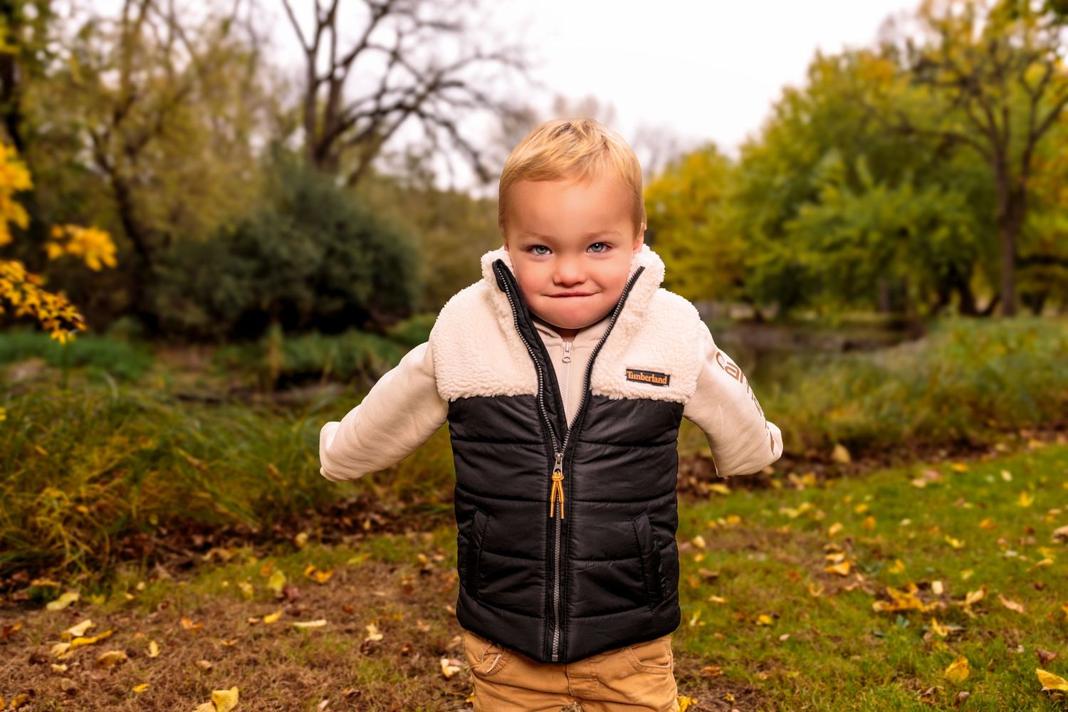 Candid outdoor portraits of children wearing black vests and light colored shirts in an autumn setting.