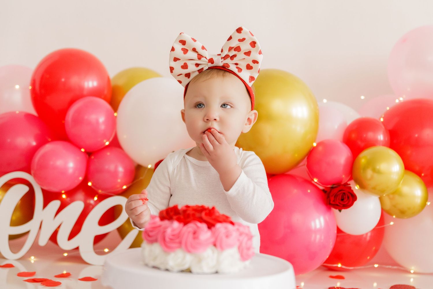 Valentine's themed balloon arch with red, gold, and white balloons and decorative text.