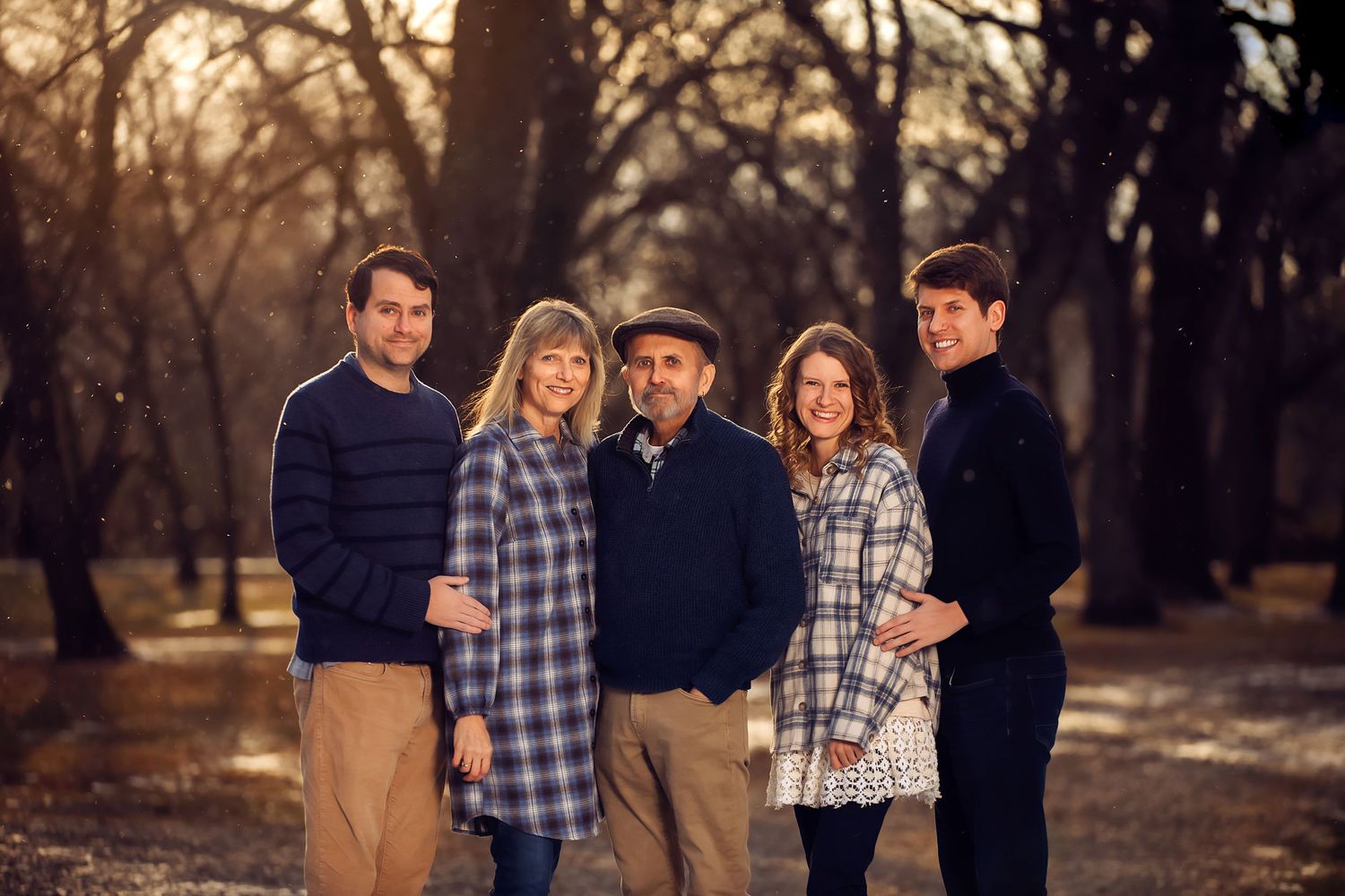 A group of people in casual attire pose together at sunset in a wooded outdoor setting.