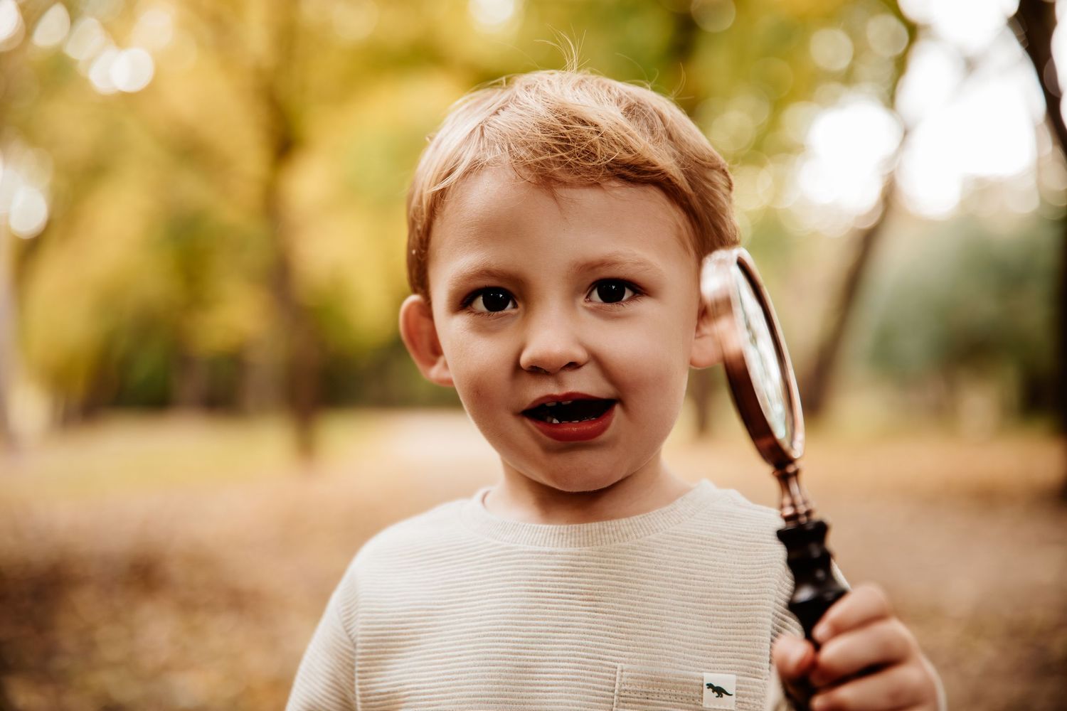 A child smiles brightly during an outdoor autumn photo session.