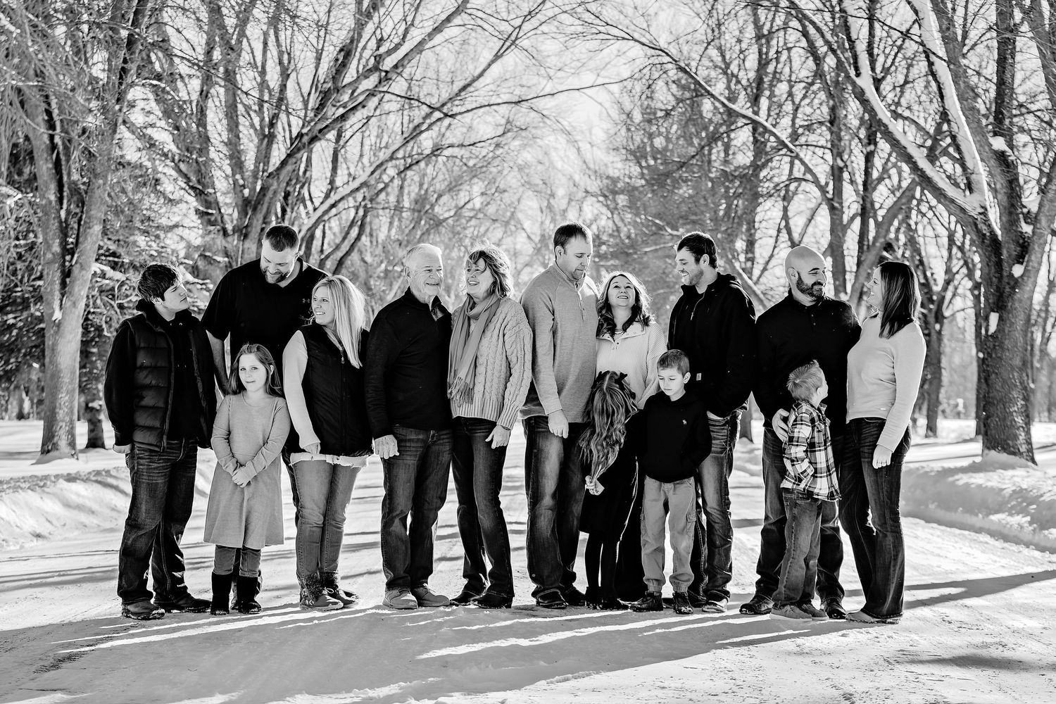 A group of people walking together on a snowy path lined with bare winter trees.