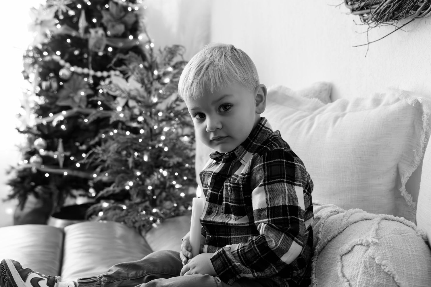 Candid holiday photos of child relaxing on white sofa with Christmas decorations visible.
