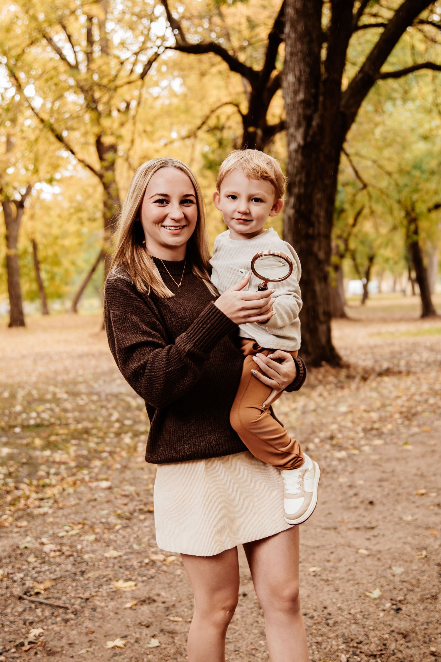 Family enjoying autumn moments together in a wooded park with golden fall foliage.