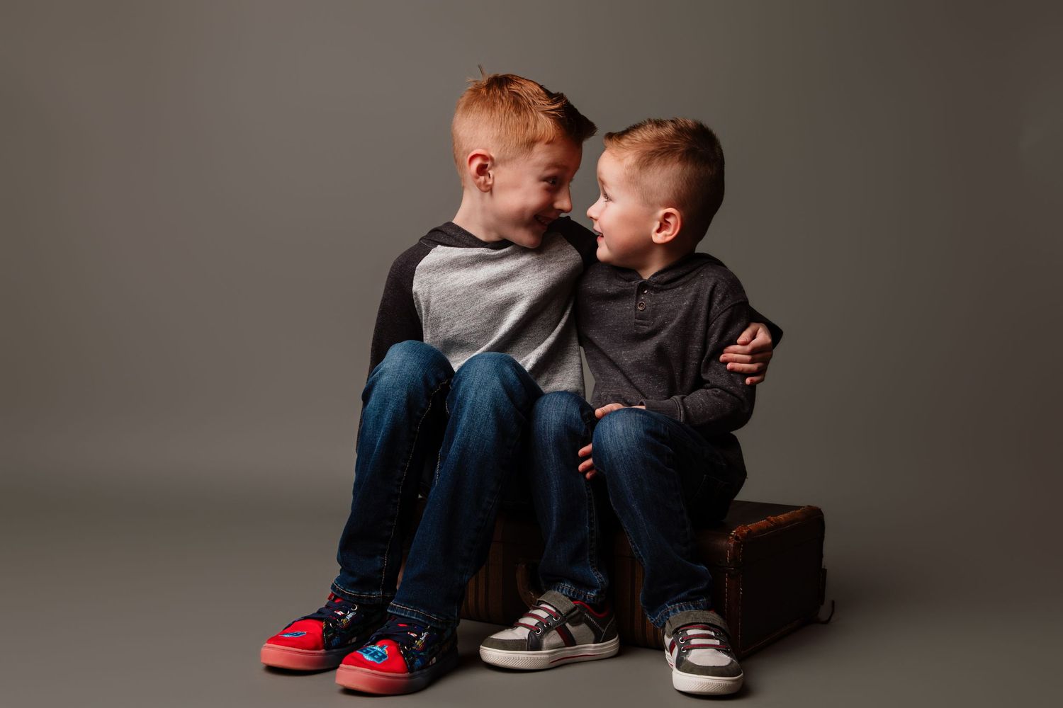 A series of black and white photographs showing a parent and child sitting together on a dark background.