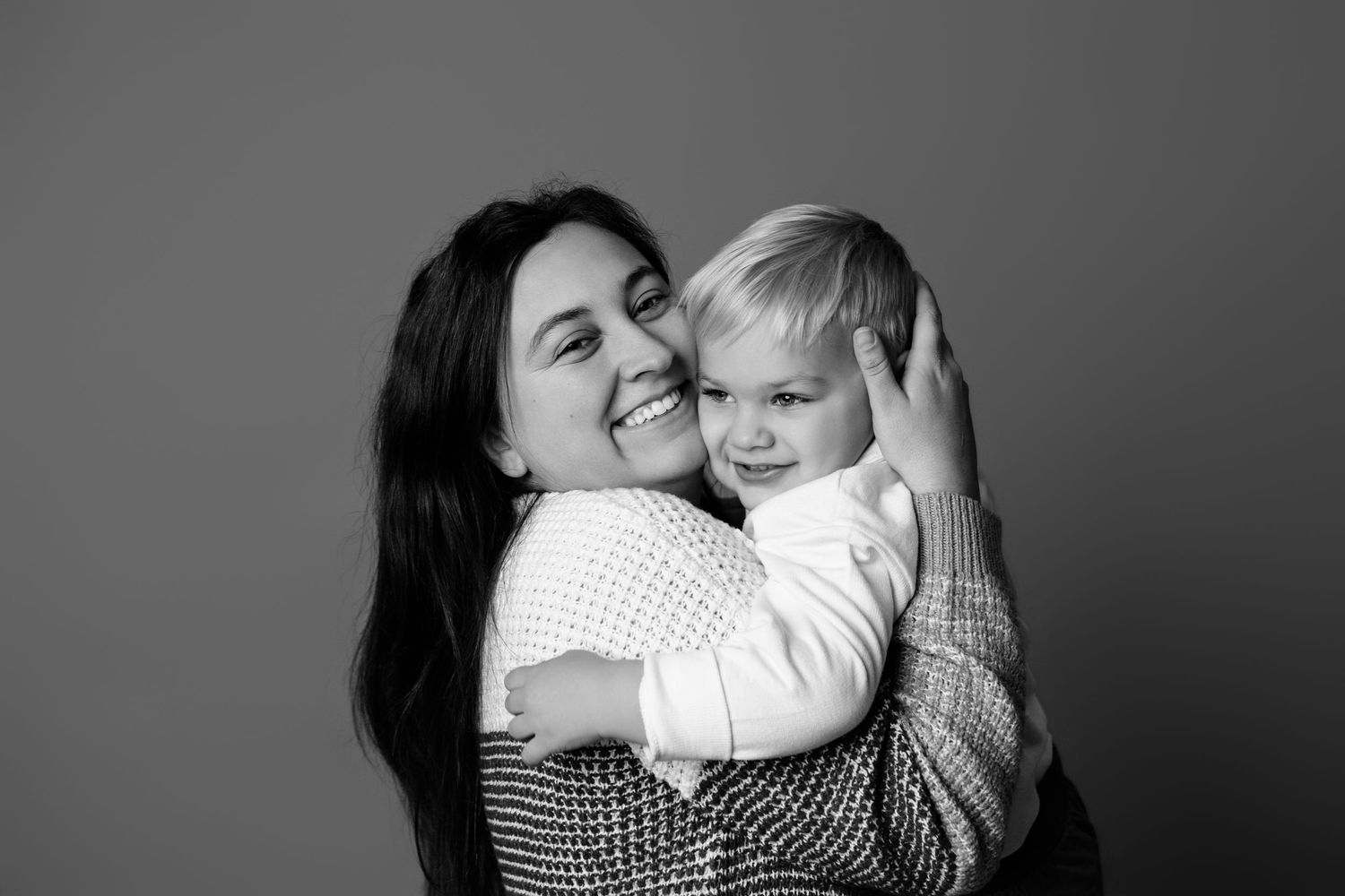 A series of black and white photos showing tender moments between a parent and child embracing.