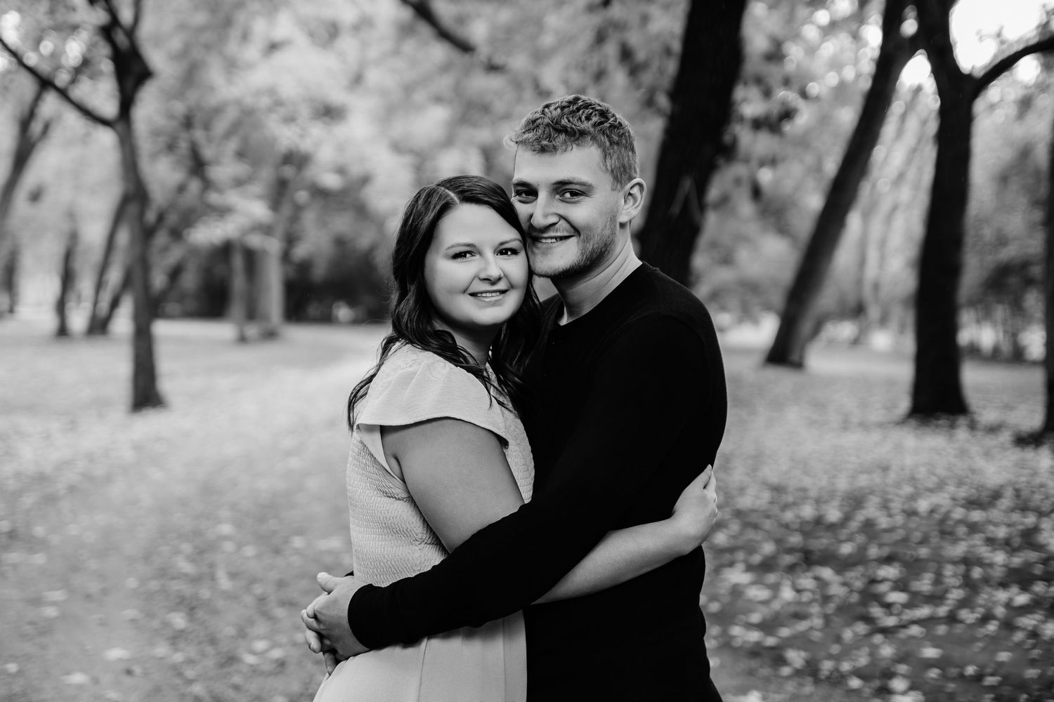 Loving family embrace photographed in black and white outdoor setting.