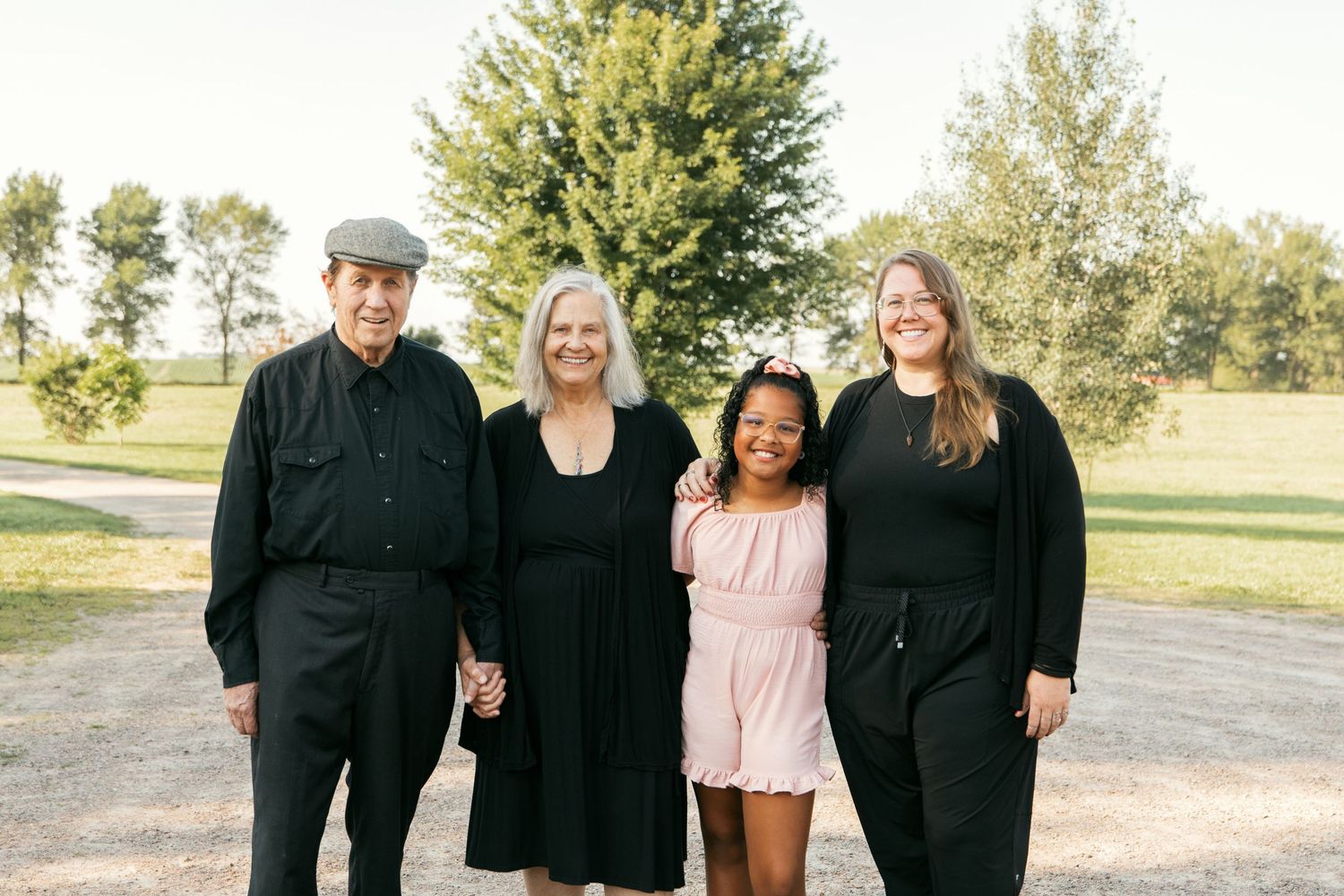Group of people in coordinated black and pink outfits standing together outdoors on a sunny day.