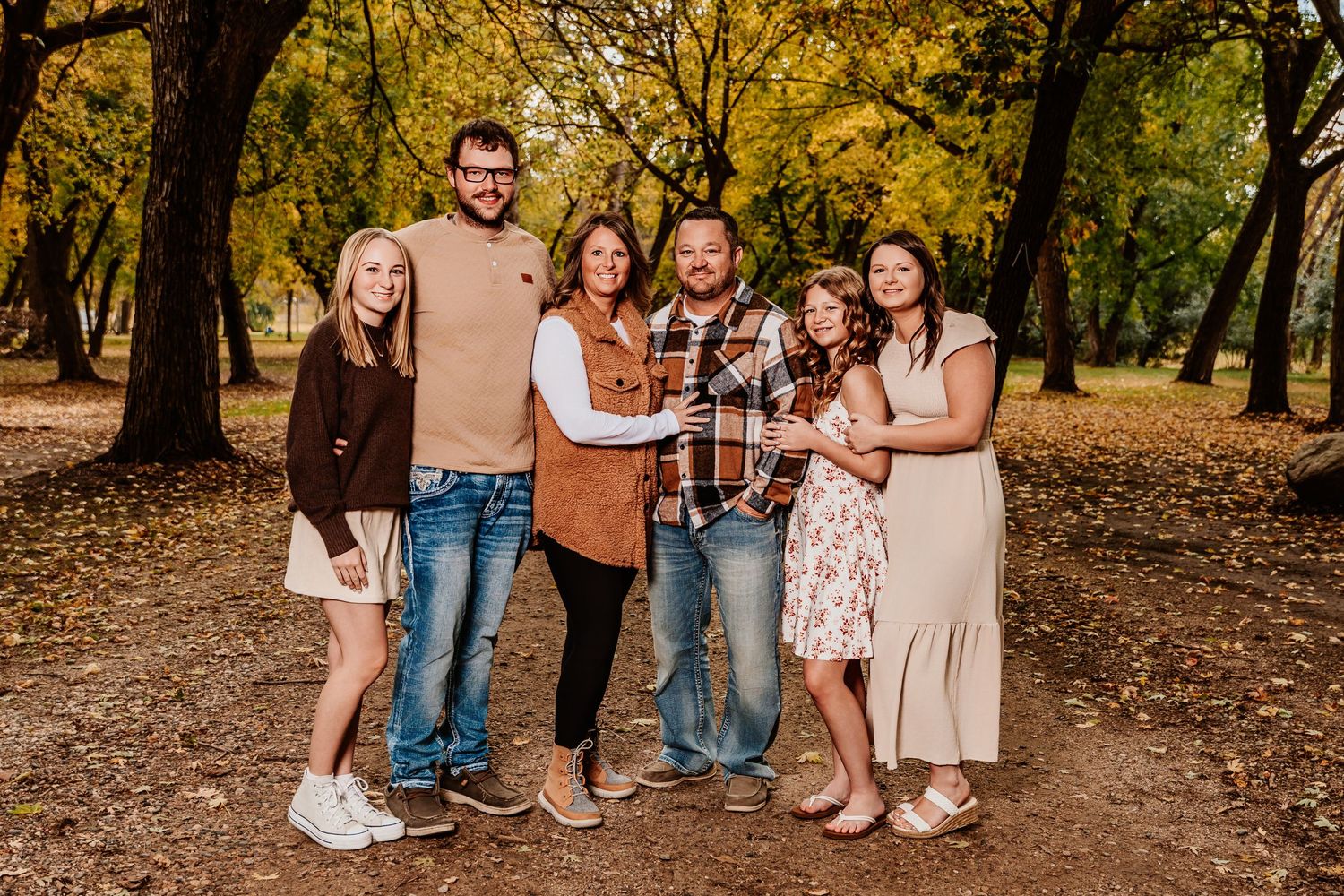 A group enjoying a playful moment together in an autumn park setting with golden foliage.