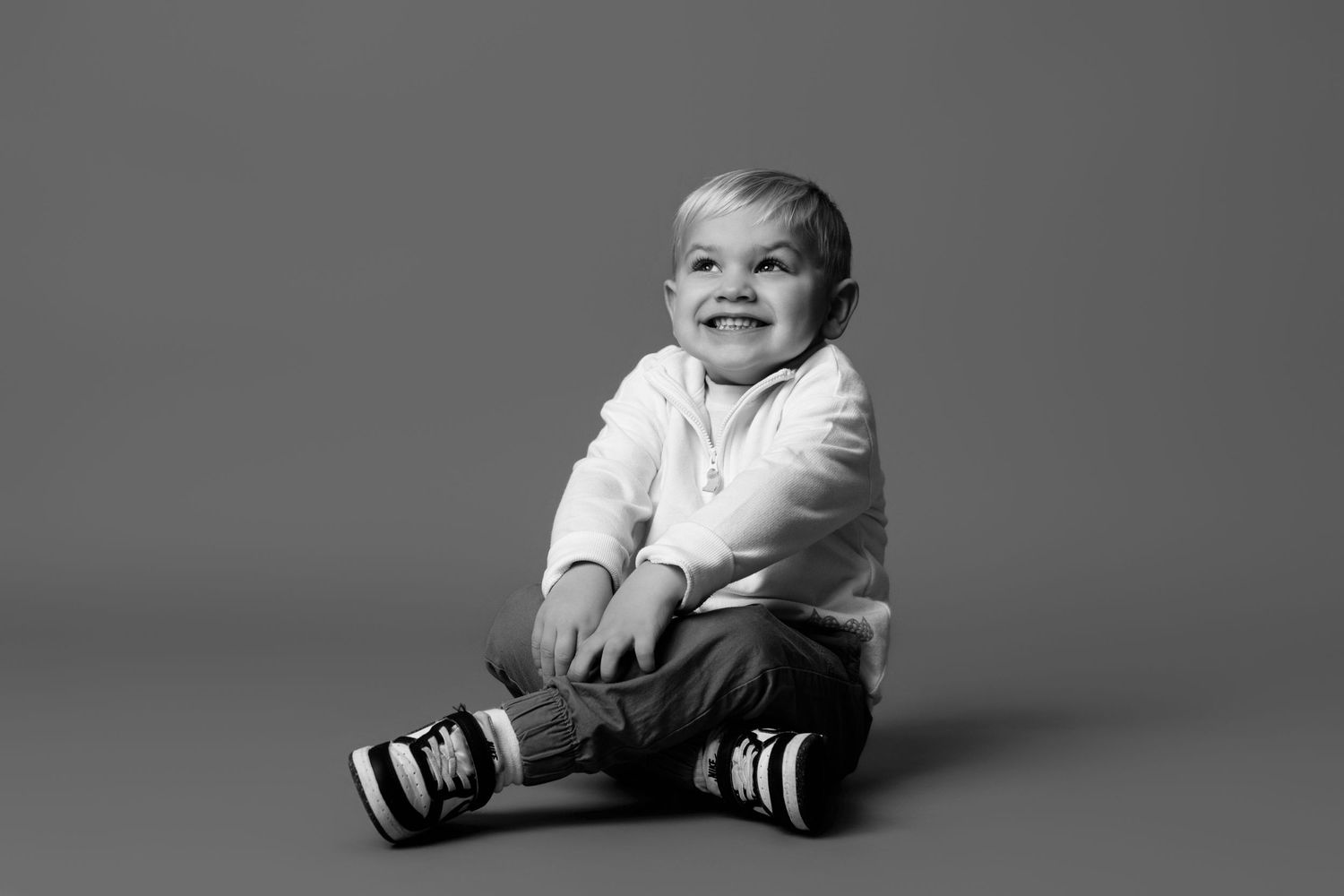Black and white photo sequence showing a baby sitting, smiling and laughing while wearing striped socks.