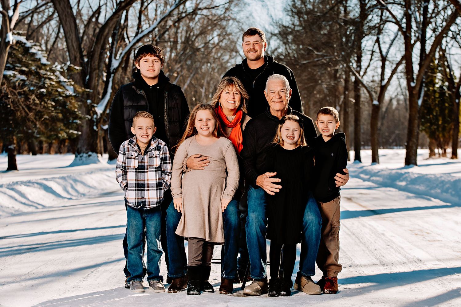 A group poses together outdoors on a snowy winter day with bare trees in the background.