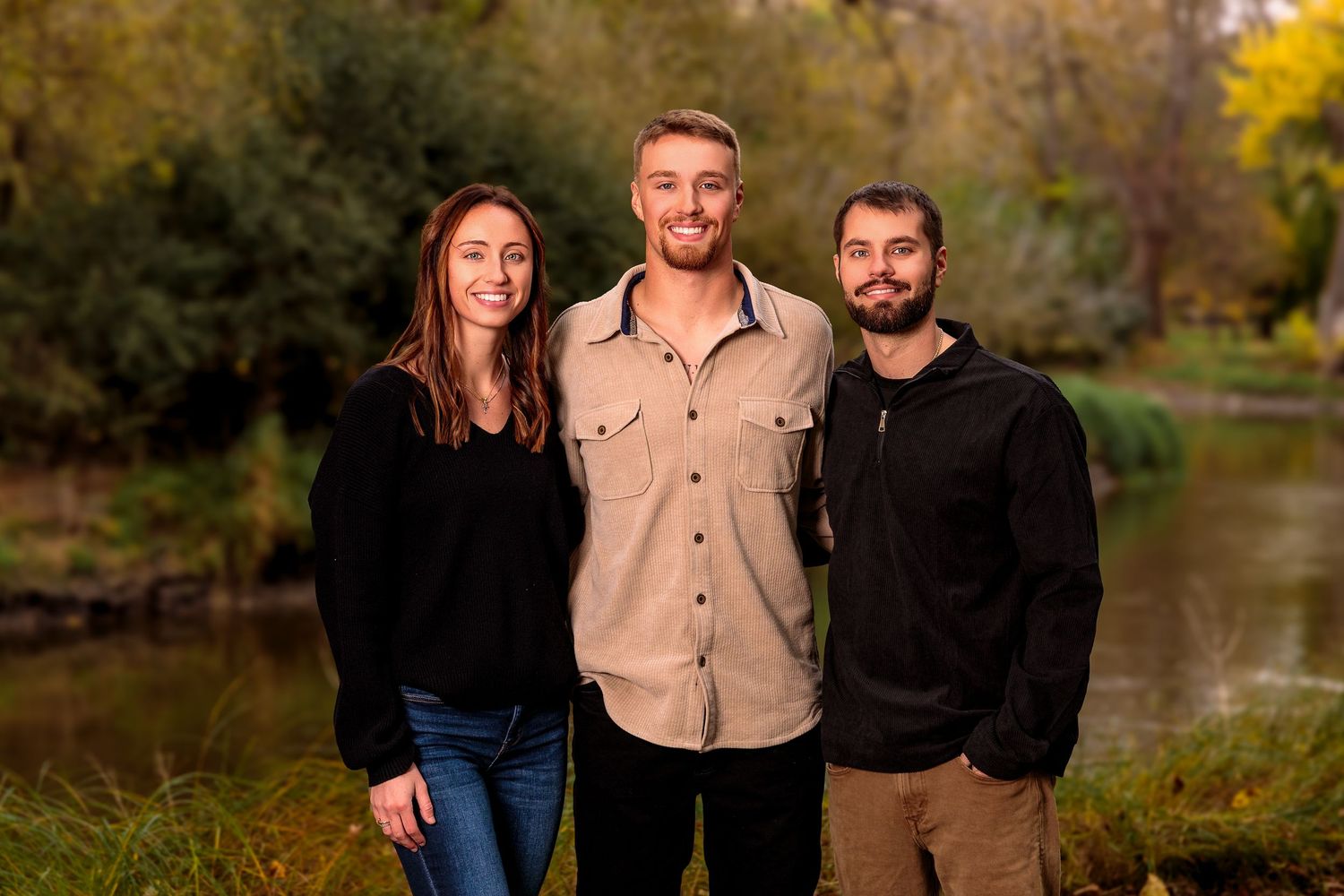 Group photo outdoors with autumn trees and lake in background.