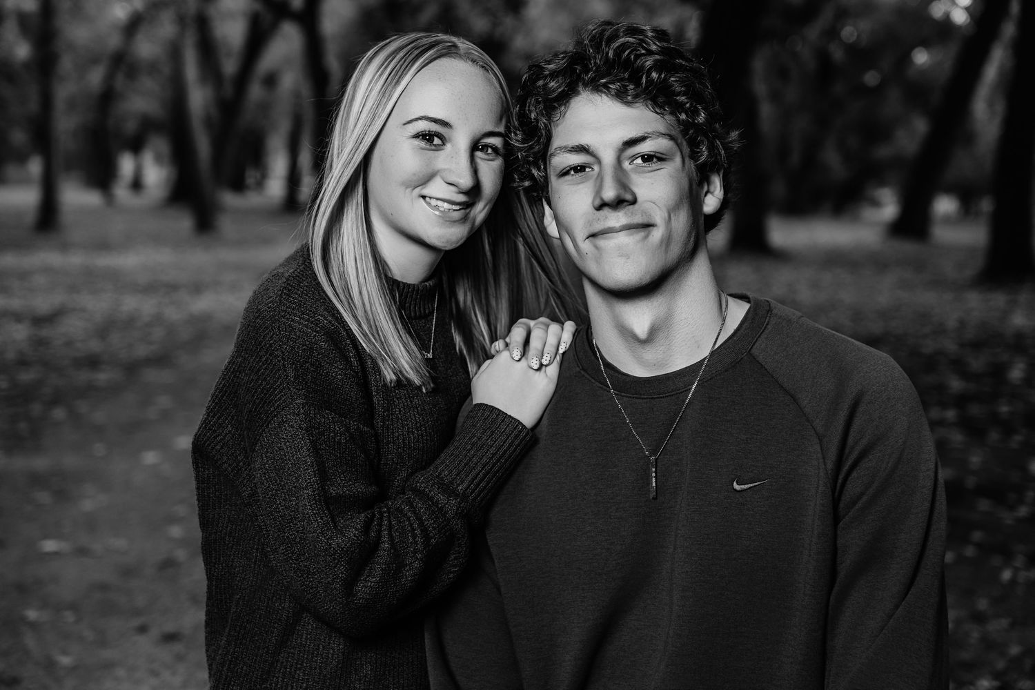 Black and white photo of a couple sharing an intimate moment outdoors.