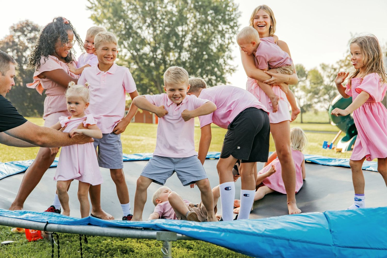 Group of people sitting on blue mats in a sunny outdoor park setting.