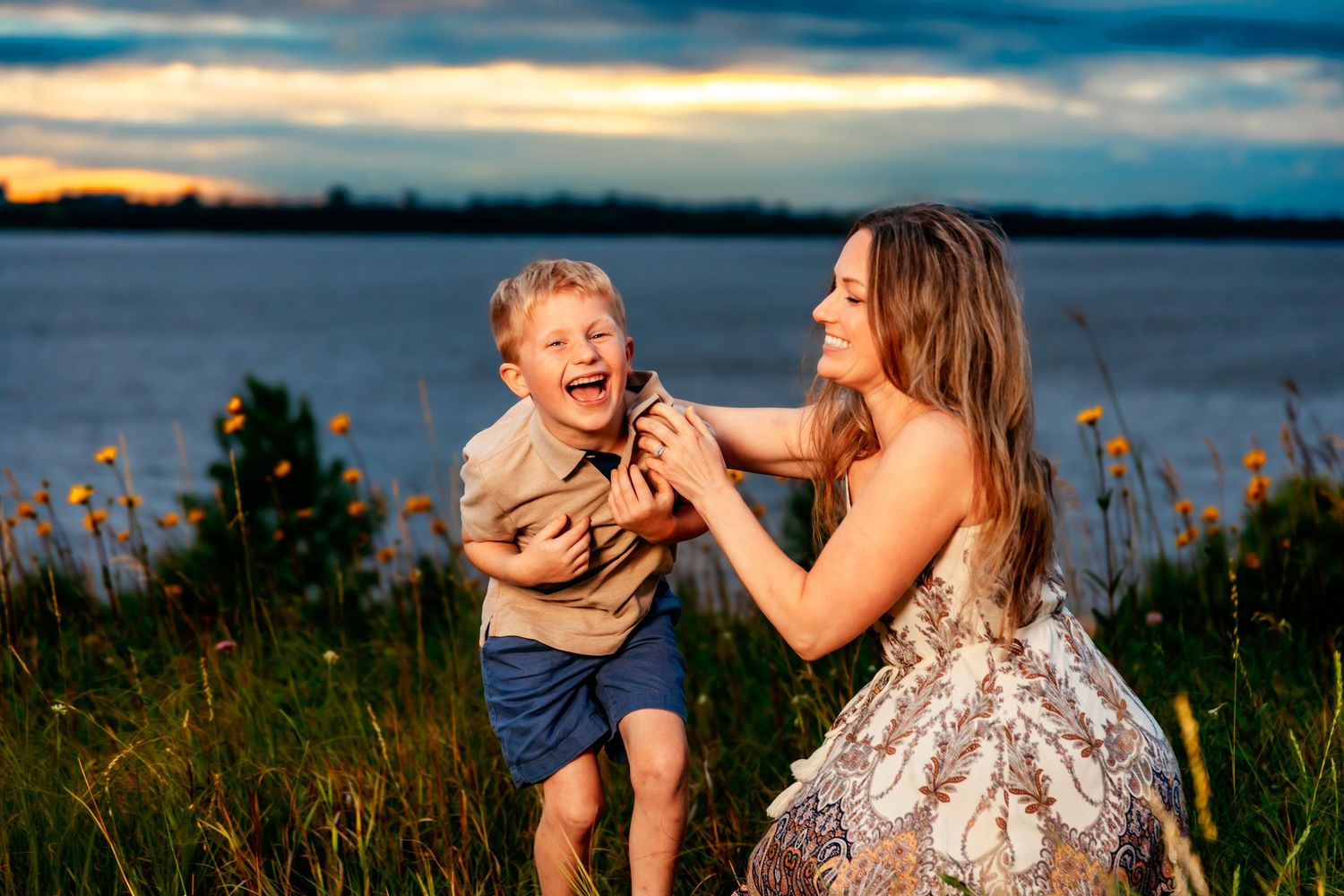 A joyful family plays together in a field at sunset with warm golden light and coastal scenery.