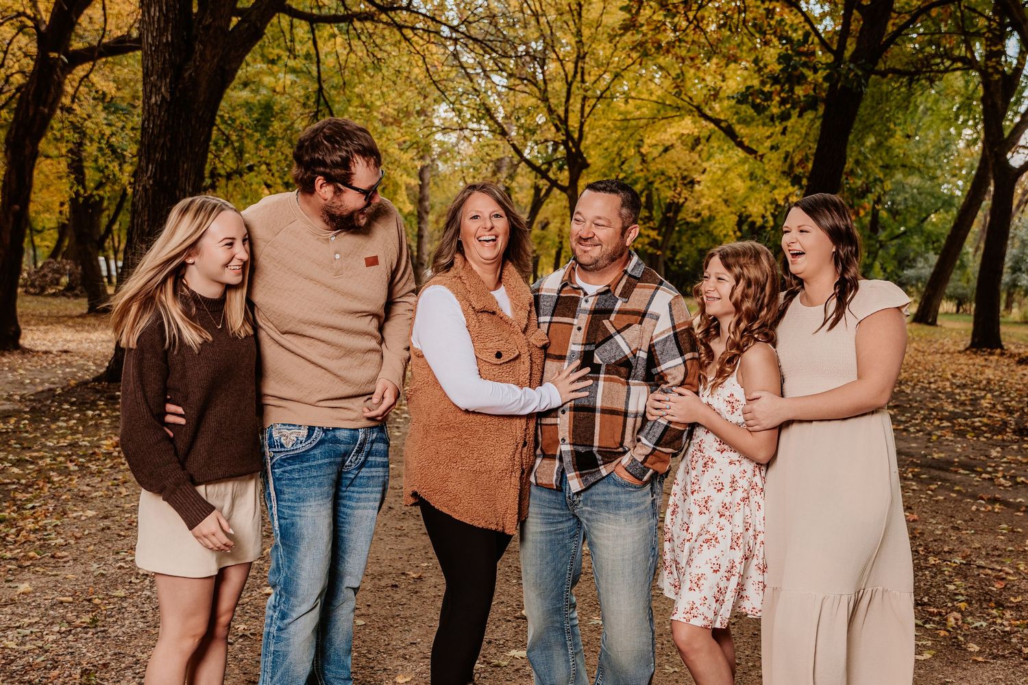 Candid laughter and joy captured during a fall photo session outdoors with warm autumn colors.