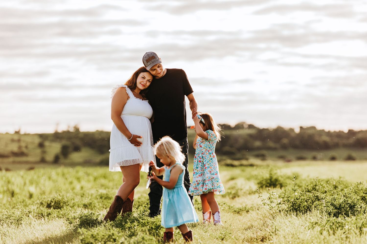 Family enjoying a playful moment together in a sunlit meadow during golden hour.
