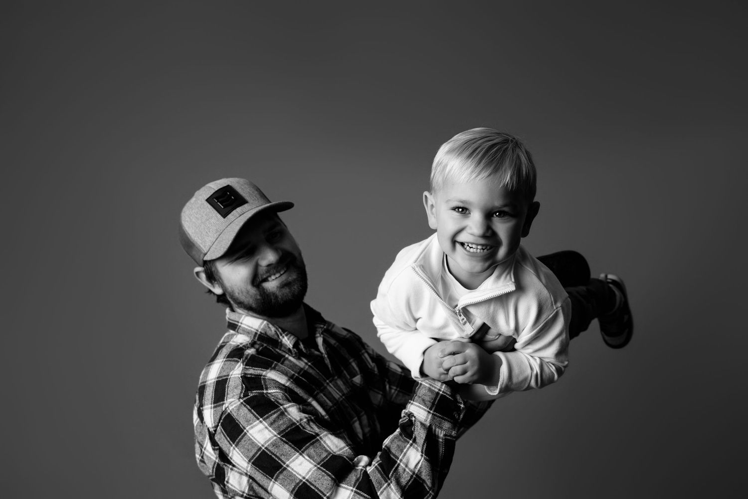 A series of black and white portraits showing playful expressions and movements in a studio setting.