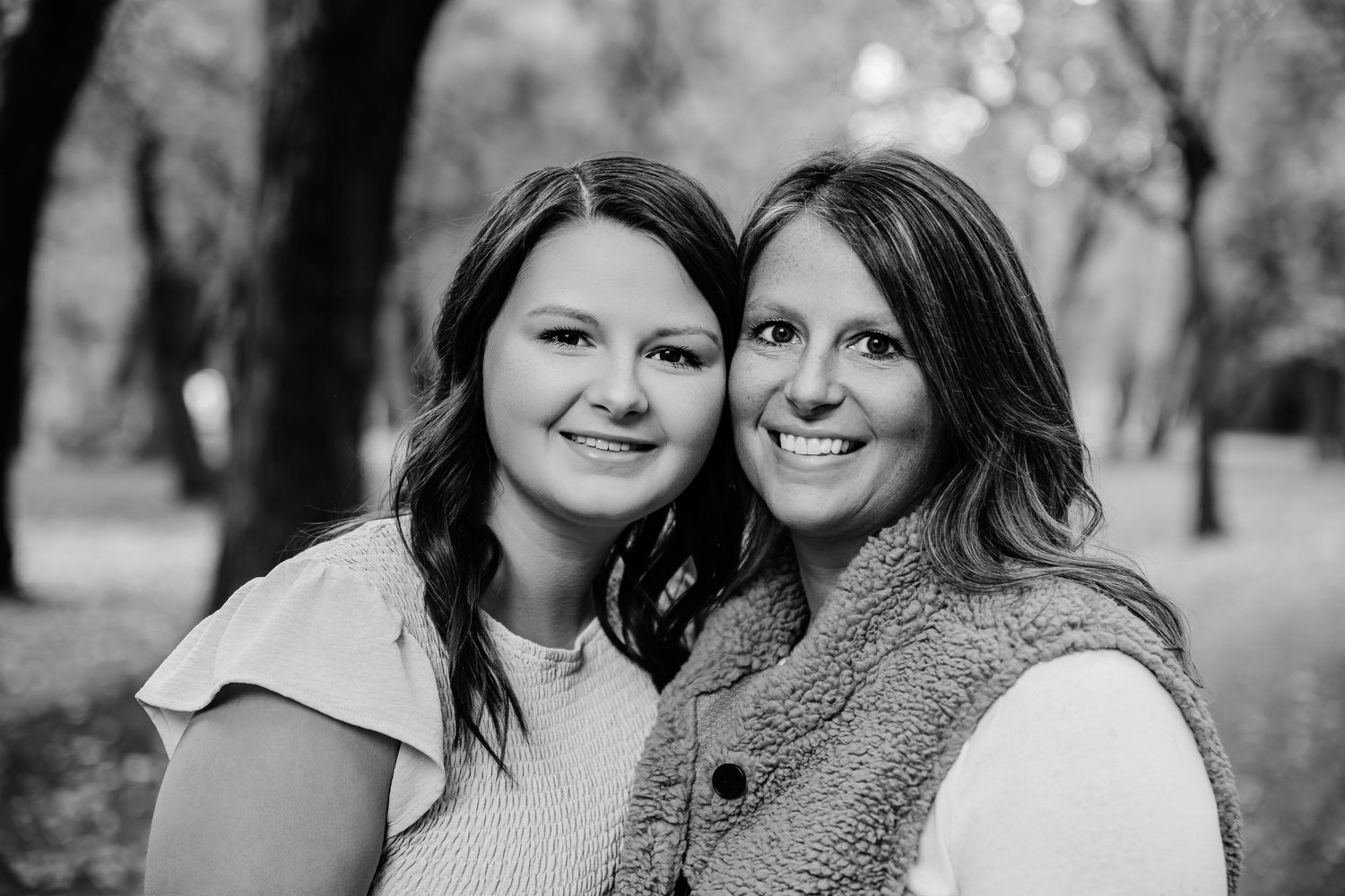 Black and white portrait of two people sharing a close moment outdoors.