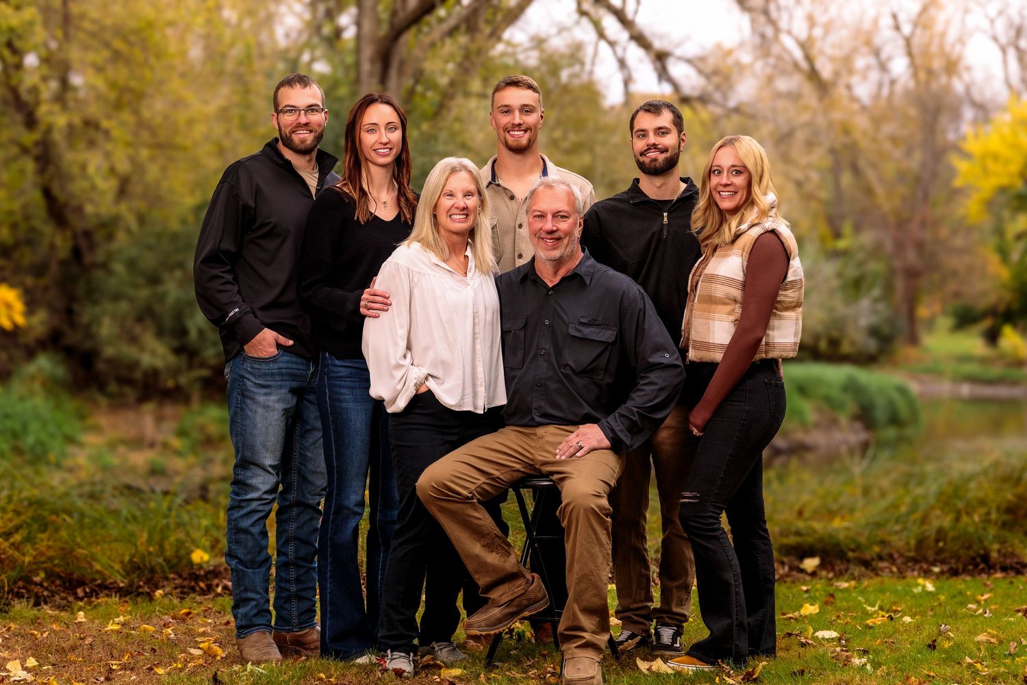 Extended family gathering outdoors during fall season with golden autumn colors.