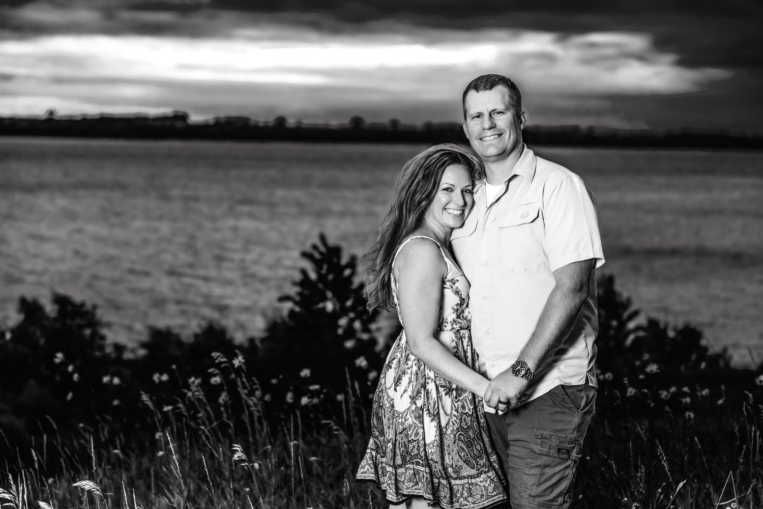 Series of black and white family portraits captured against a moody sky and grassland landscape.
