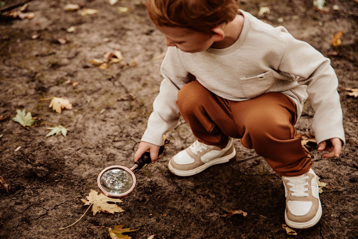Close-up view of small feet in white shoes exploring dirt and leaves.