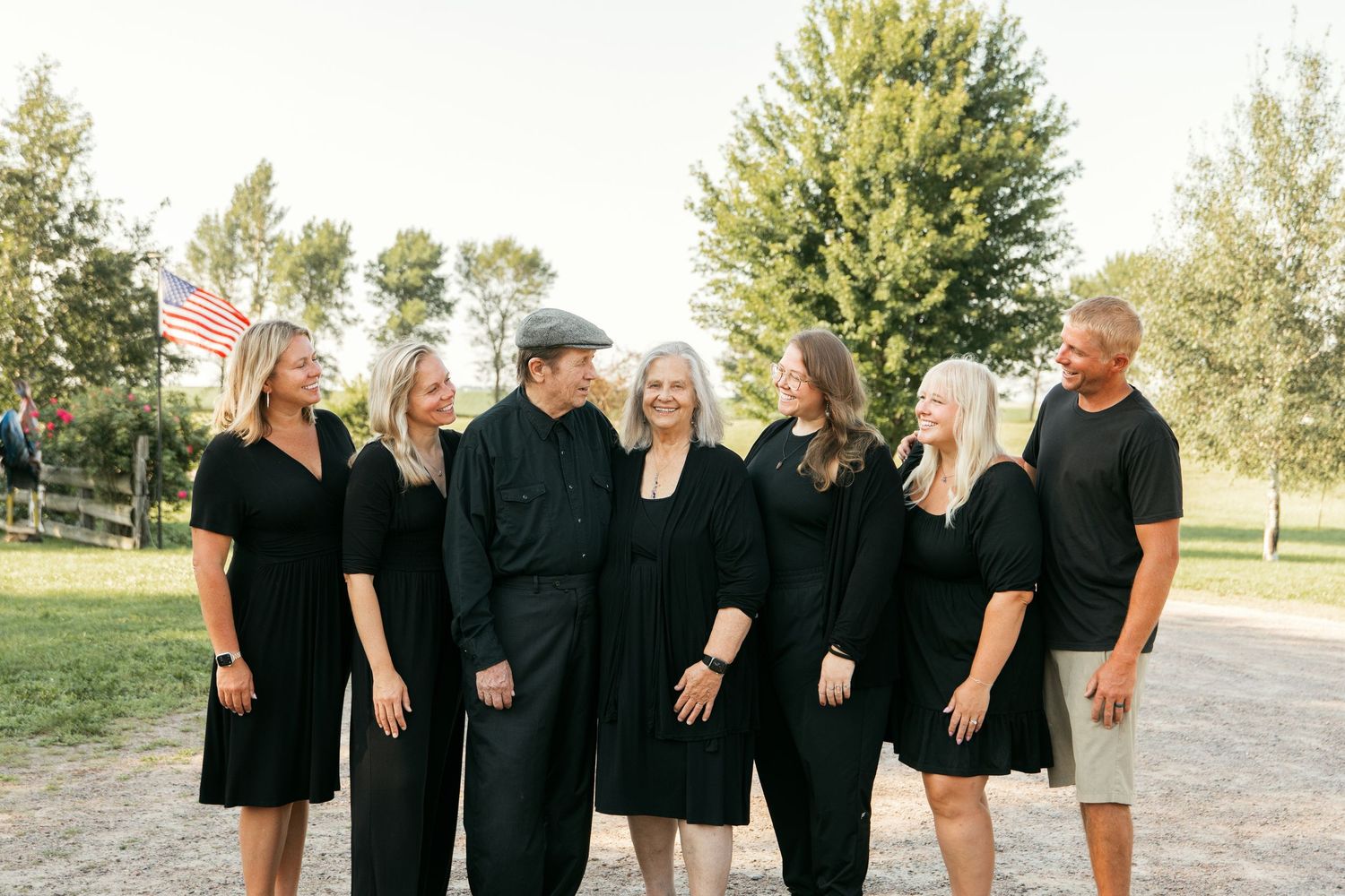 Family members wearing coordinated black outfits pose together outdoors for a casual group photo session.