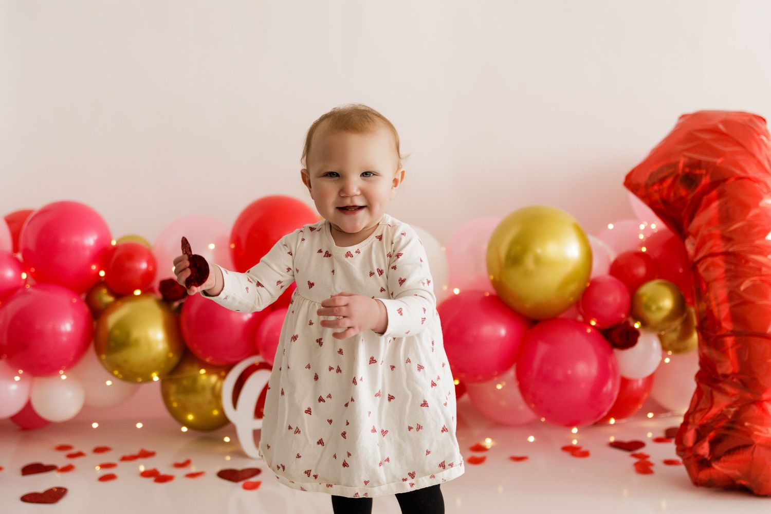 Valentine's themed party setup with pink and gold balloons and heart decorations.