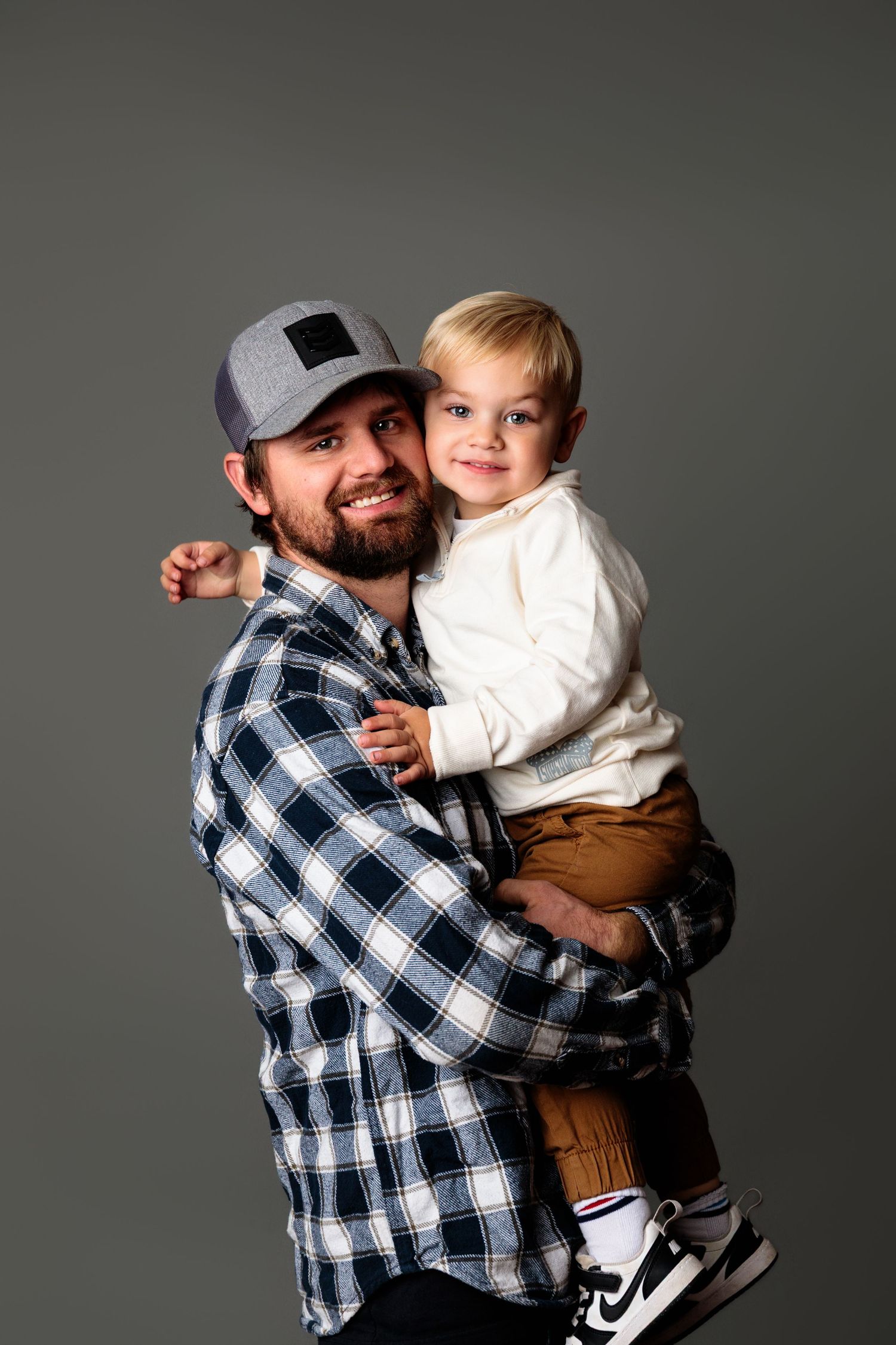 Heartwarming moment of parent and child embracing while wearing plaid shirt and casual attire.