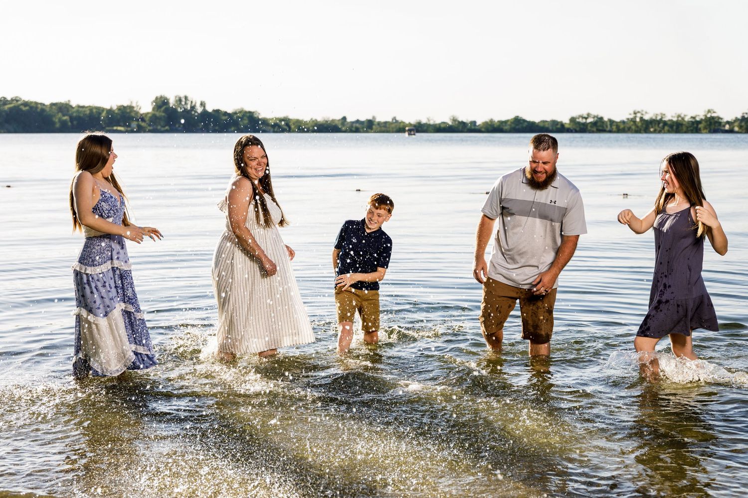 Happy family of five splashing and playing together in a lake during an outdoor photo session.