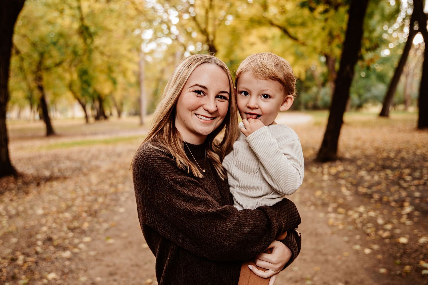 Family enjoying a tender moment together in an autumn park setting with golden leaves.