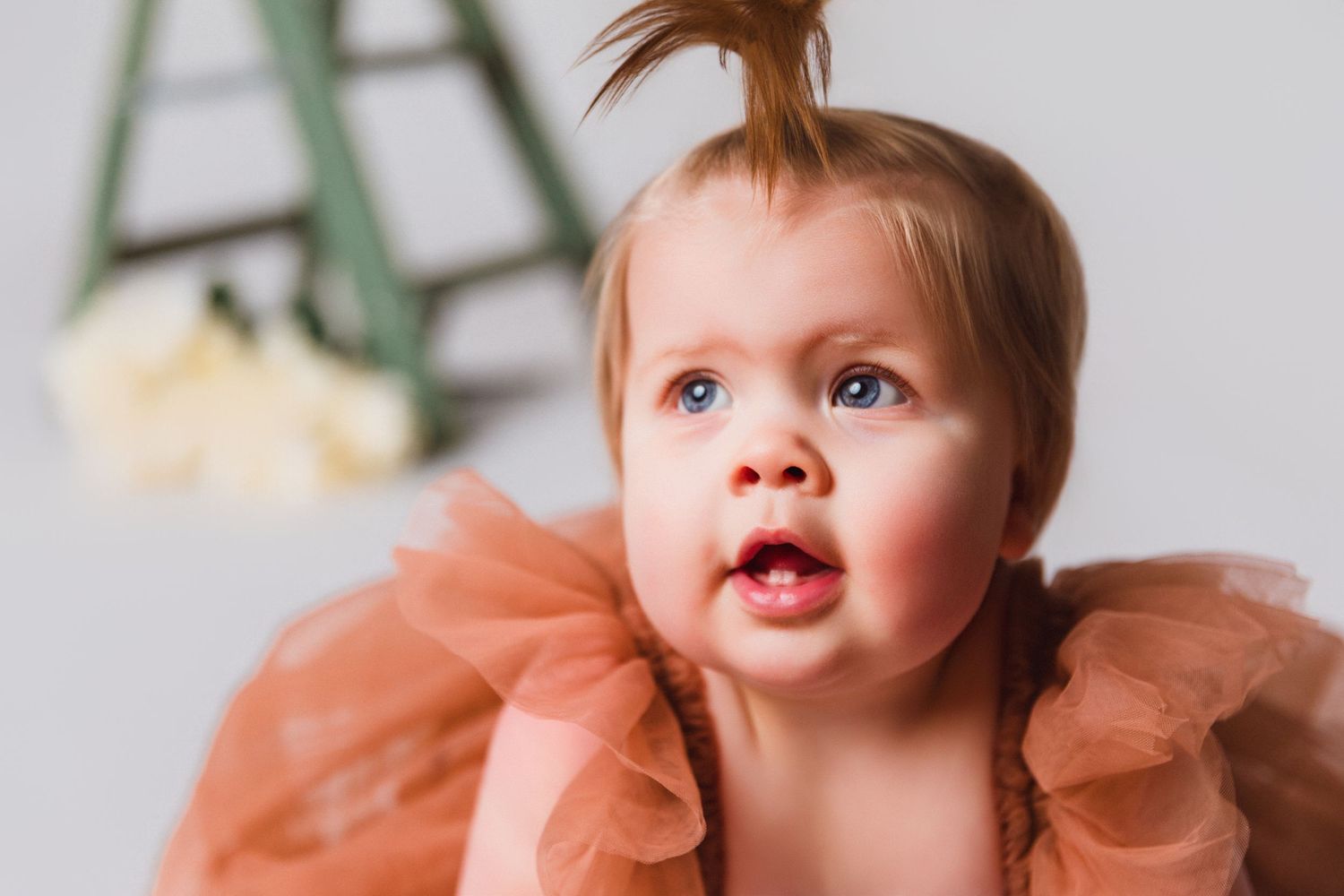 Close-up shots of baby in peachy tulle dress showing various expressions.