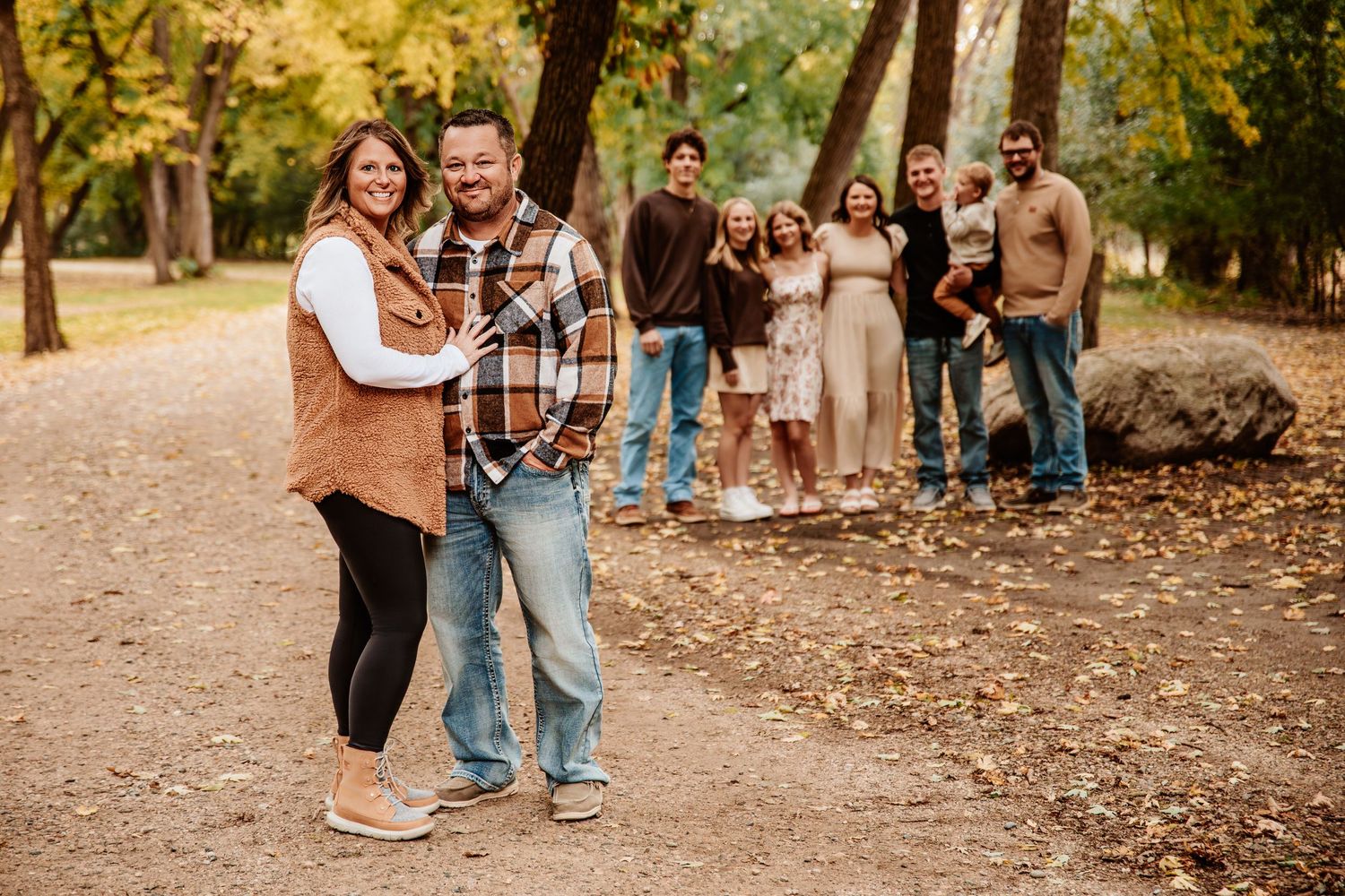 Group walking together on a leaf-covered path in a wooded park during golden hour.