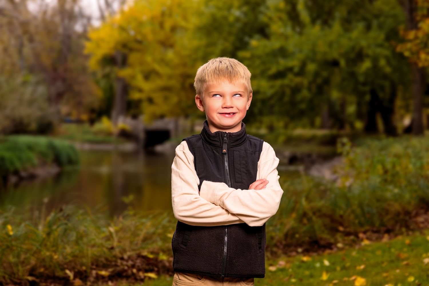 An autumn outdoor portrait with someone wearing a black vest against golden fall foliage.