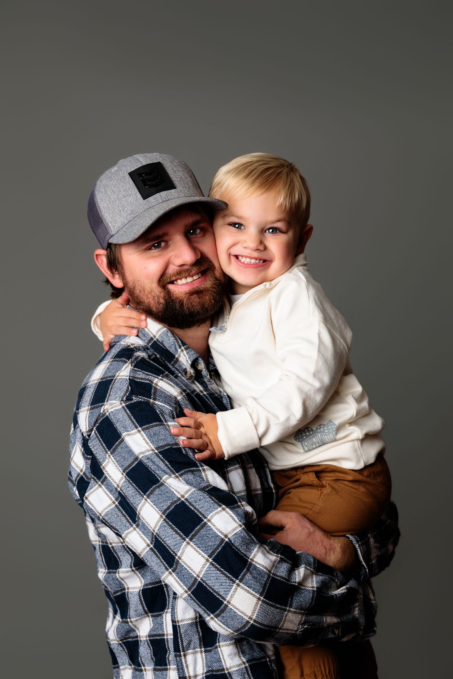 Heartwarming studio portraits featuring plaid shirt and casual attire against gray background.
